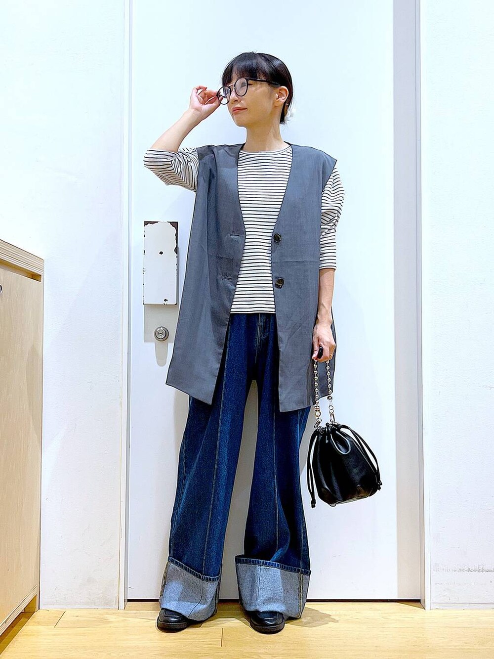 ブラック系のショルダーバッグ、ブラック系のローファー、グレー系のベストを着用したレディースの秋コーディネートの2枚目の写真