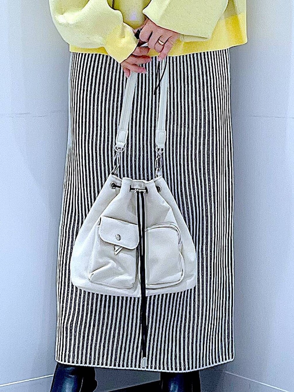 ホワイト系のショルダーバッグ、ベージュ系のスカート、ブラック系のブーツを着用したレディースの冬コーディネートの9枚目の写真