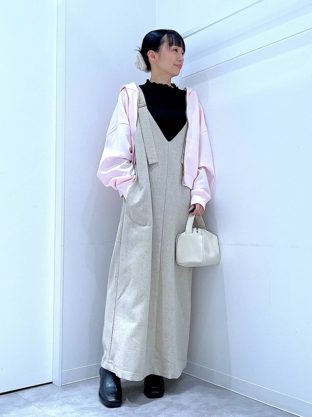 ブラック系のブーツ、ベージュ系のジャンパースカート、ブラック系のTシャツ/カットソーを着用したレディースの冬コーディネートの2枚目の写真