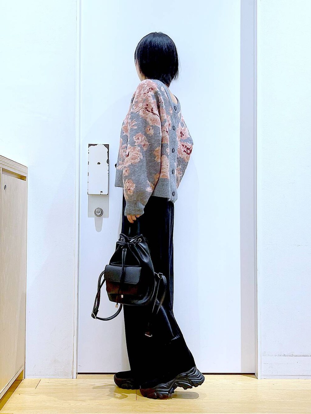 ブラック系のバックパック/リュック、ブラック系のスカート、ブラック系のブーツを着用したレディースの秋コーディネートの3枚目の写真