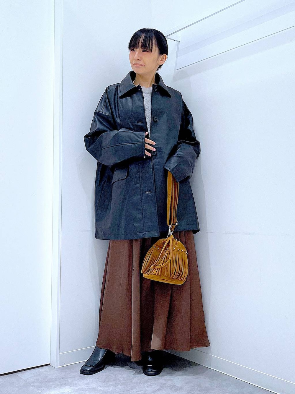 ブラック系のステンカラーコート、レッド系のニット/セーター、ブラック系のブーツを着用したレディースの冬コーディネートの2枚目の写真