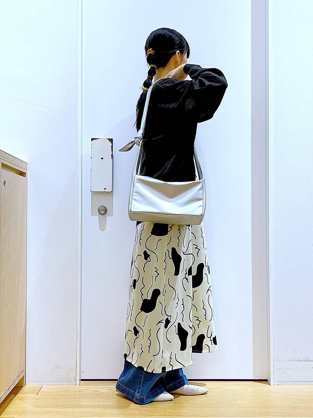 ブルー系のデニムパンツ、ベージュ系のワンピース、シルバー系のショルダーバッグを着用したレディースの春コーディネートの4枚目の写真