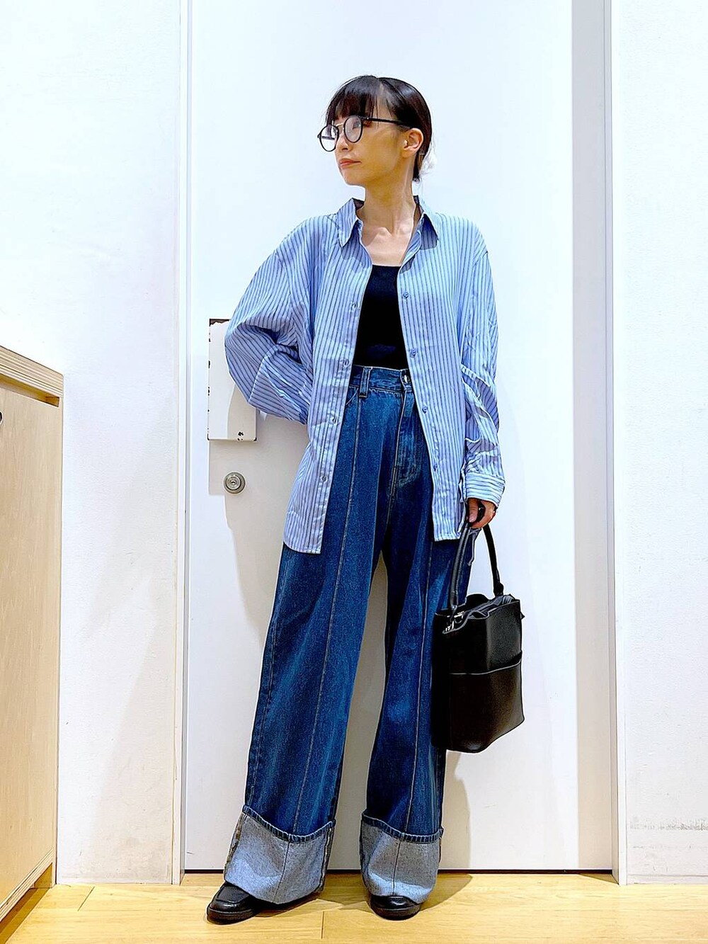 ブラック系のローファー、ブラック系のショルダーバッグ、ブルー系のシャツ/ブラウスを着用したレディースの秋コーディネートの2枚目の写真