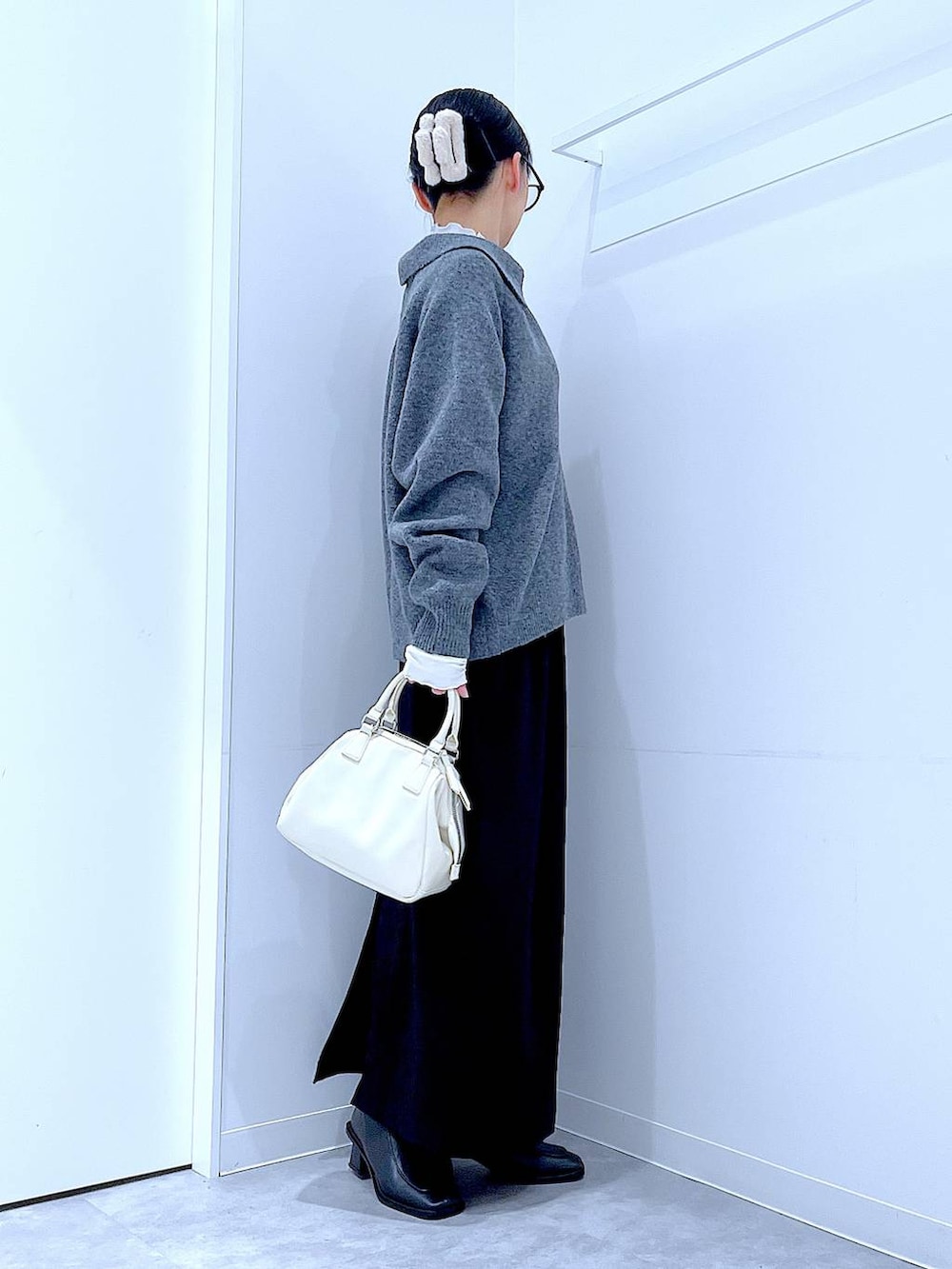 ブラック系のスカート、ブラック系のブーツ、ホワイト系のショルダーバッグを着用したレディースの冬コーディネートの4枚目の写真