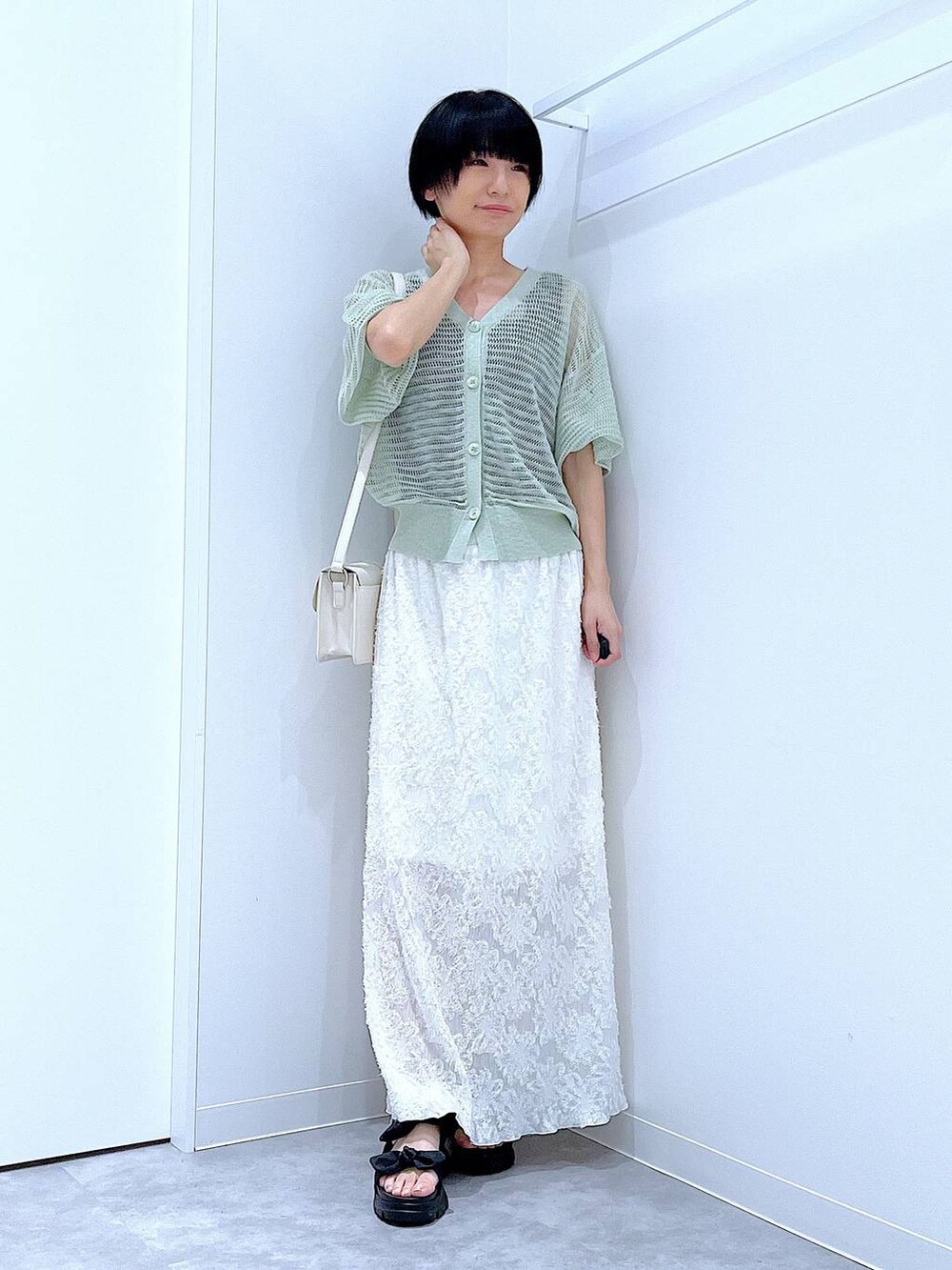 ブラック系のサンダル、ホワイト系のスカート、グリーン系のカーディガン/ボレロを着用したレディースの夏コーディネートの2枚目の写真