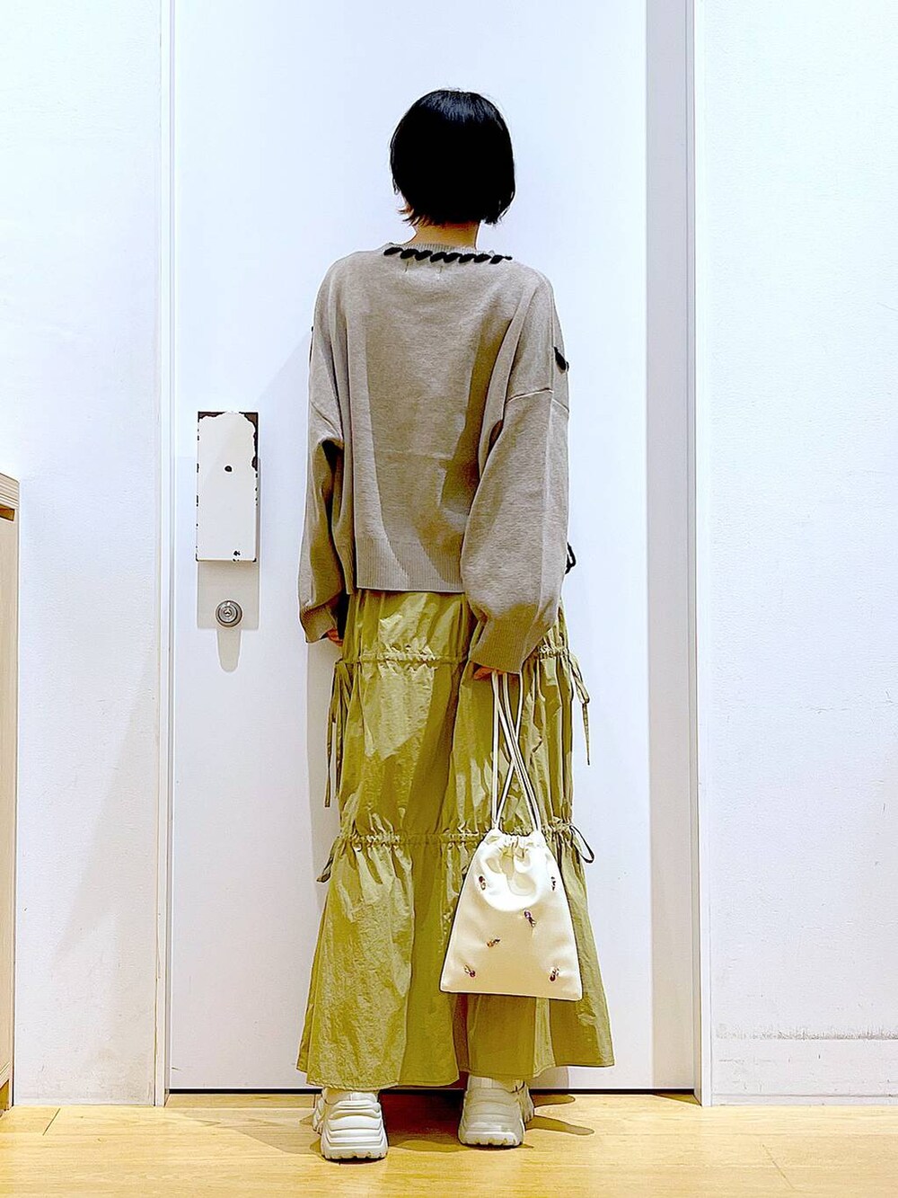 ホワイト系のショルダーバッグ、イエロー系のスカート、ベージュ系のブーツを着用したレディースの秋コーディネートの5枚目の写真