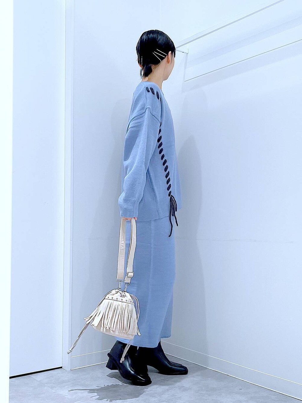 ブルー系のニット/セーター、ブルー系のスカート、ブラック系のブーツを着用したレディースの秋コーディネートの4枚目の写真