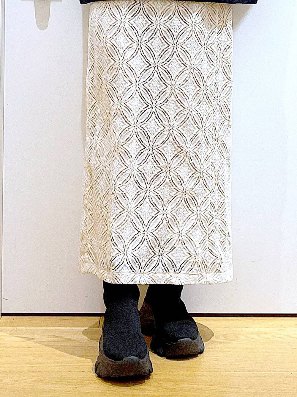 ブラック系のブーツ、ホワイト系のスカート、ブラック系のショルダーバッグを着用したレディースの冬コーディネートの8枚目の写真