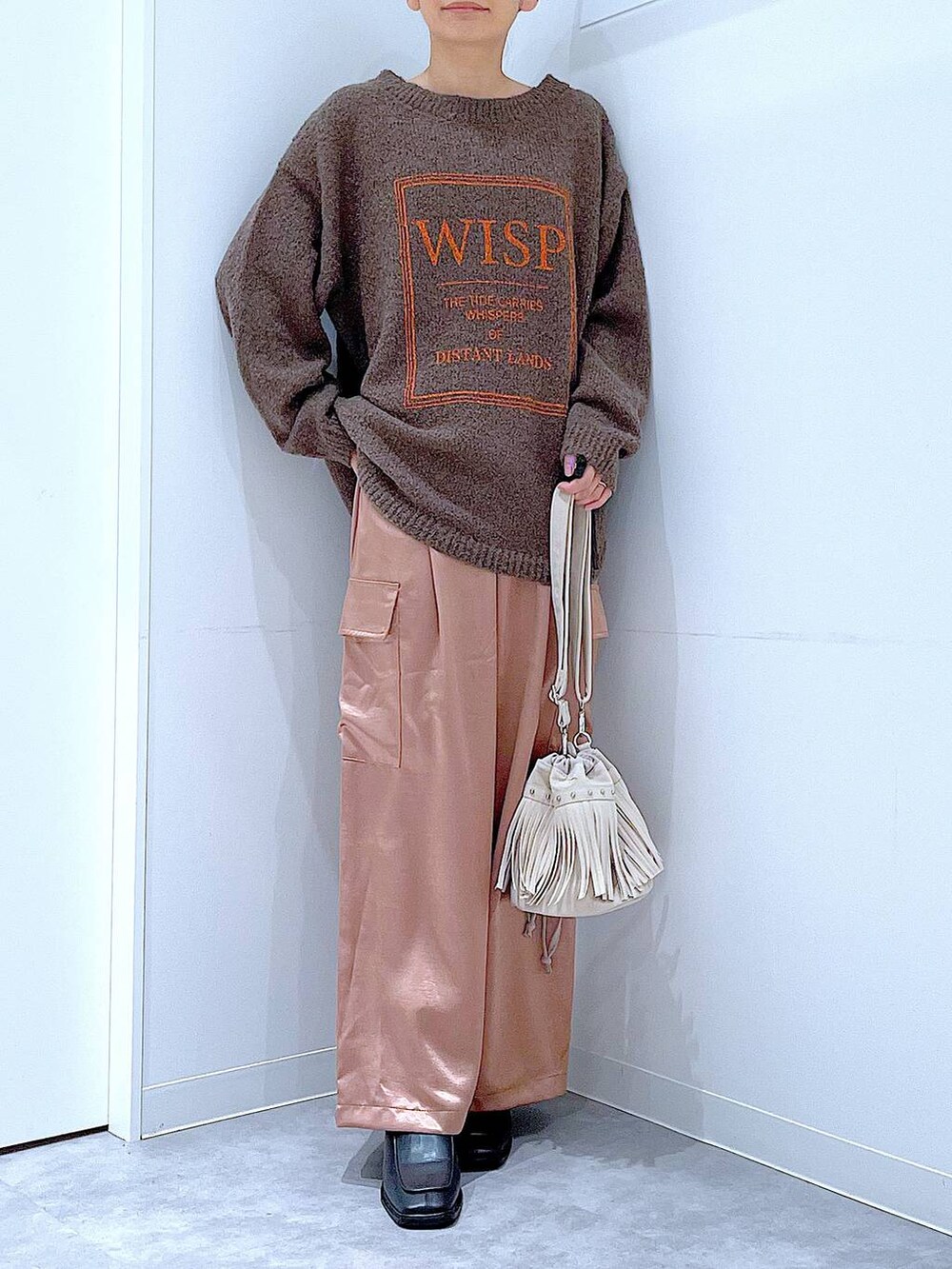 ブラウン系のニット/セーター、ブラック系のブーツ、ホワイト系のショルダーバッグを着用したレディースの冬コーディネートの6枚目の写真