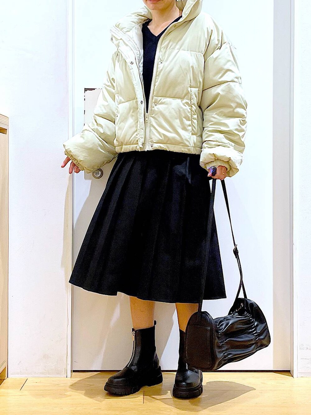 イエロー系のブルゾン、ブラック系のブーツ、ブラック系のスカートを着用したレディースの冬コーディネートの6枚目の写真