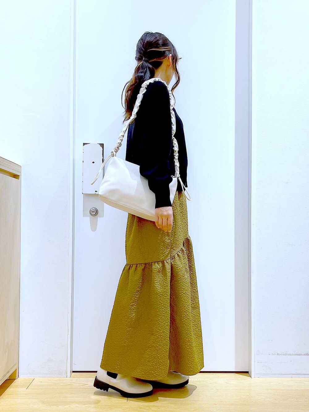 ホワイト系のショルダーバッグ、ベージュ系のブーツ、ブラック系のニット/セーターを着用したレディースの冬コーディネートの5枚目の写真