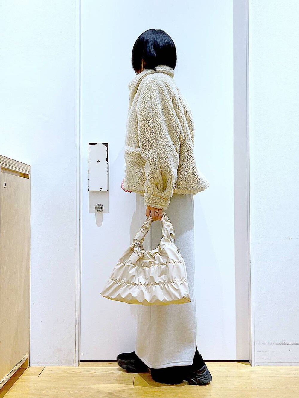 ホワイト系のブルゾン、ブラック系のブーツ、ベージュ系のスカートを着用したレディースの冬コーディネートの3枚目の写真