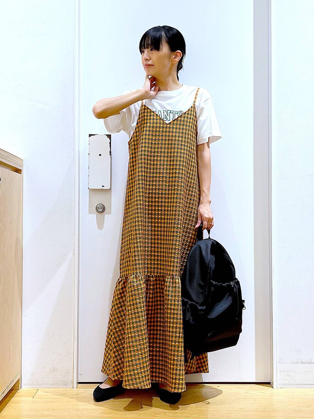 オレンジ系のワンピース、ブラック系のバックパック/リュック、ブラック系のパンプスを着用したレディースの春コーディネートの2枚目の写真