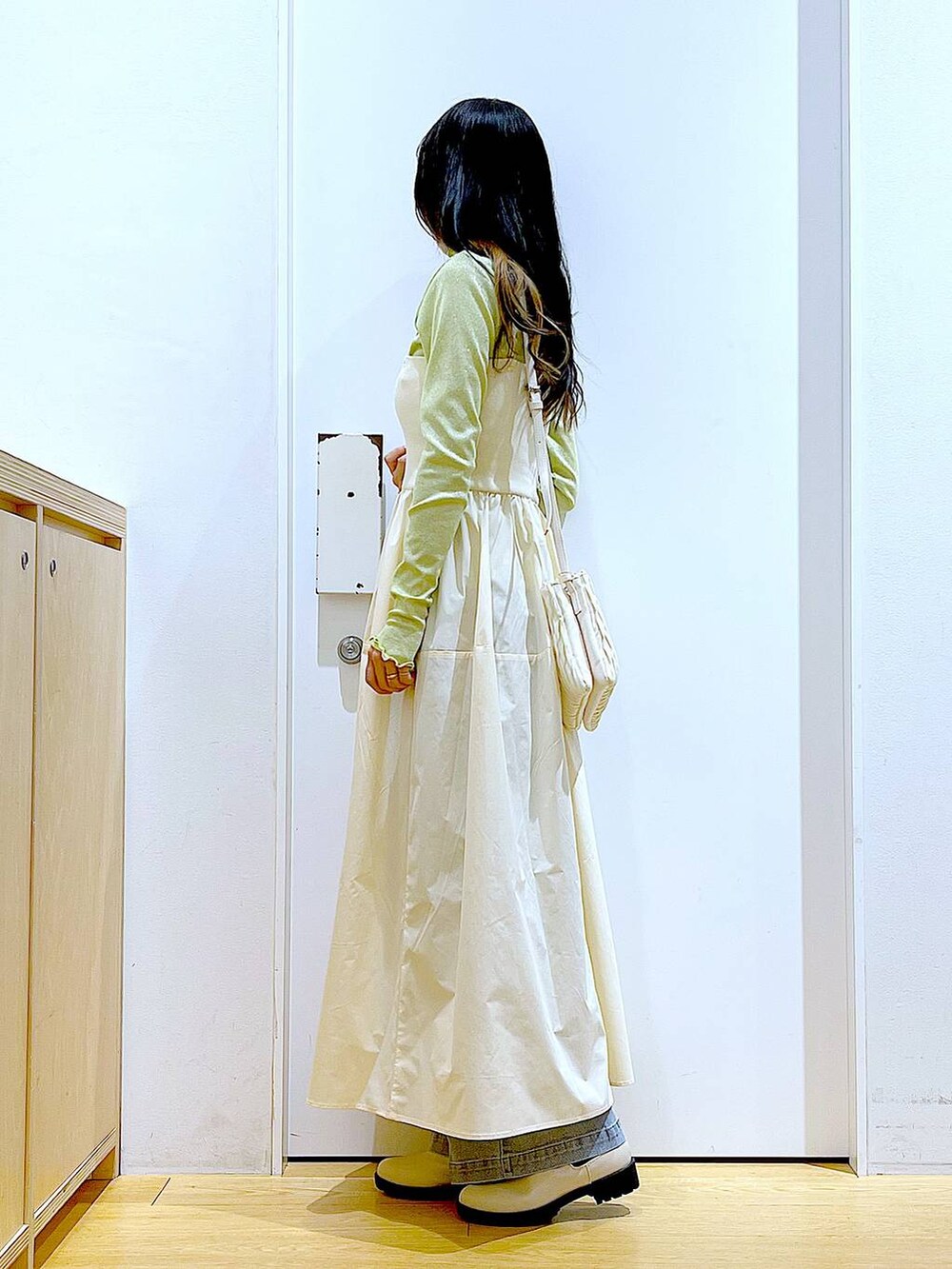 ホワイト系のショルダーバッグ、ベージュ系のブーツ、ブルー系のデニムパンツを着用したレディースの冬コーディネートの3枚目の写真