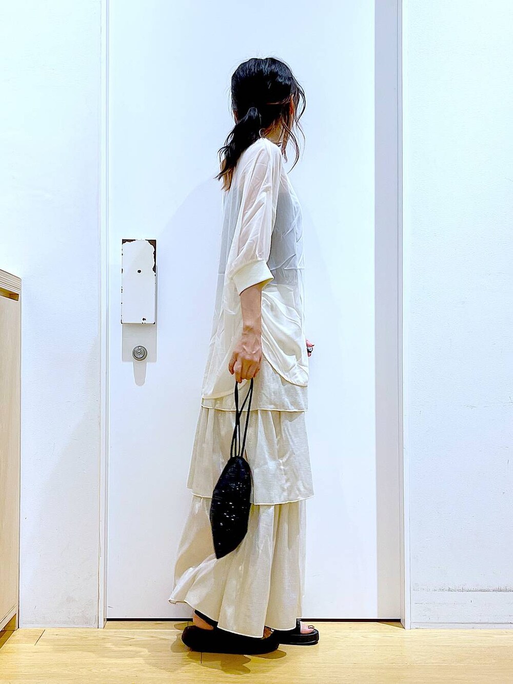 ブラック系のサンダル、ブラック系のショルダーバッグ、ゴールド系のスカートを着用したレディースの夏コーディネートの4枚目の写真