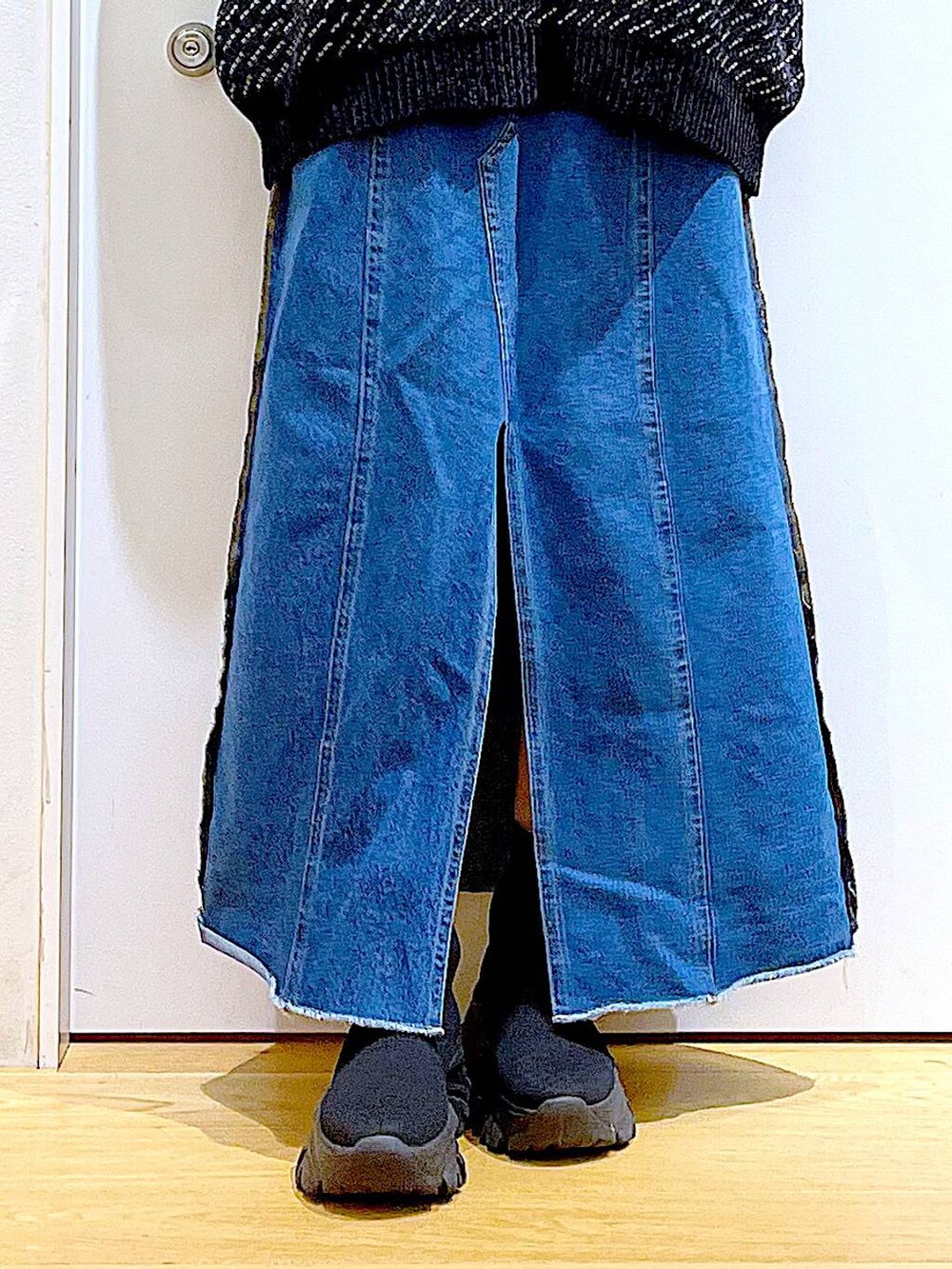 レッド系のショルダーバッグ、ブルー系のデニムスカート、ブラック系のニット/セーターを着用したレディースの冬コーディネートの8枚目の写真