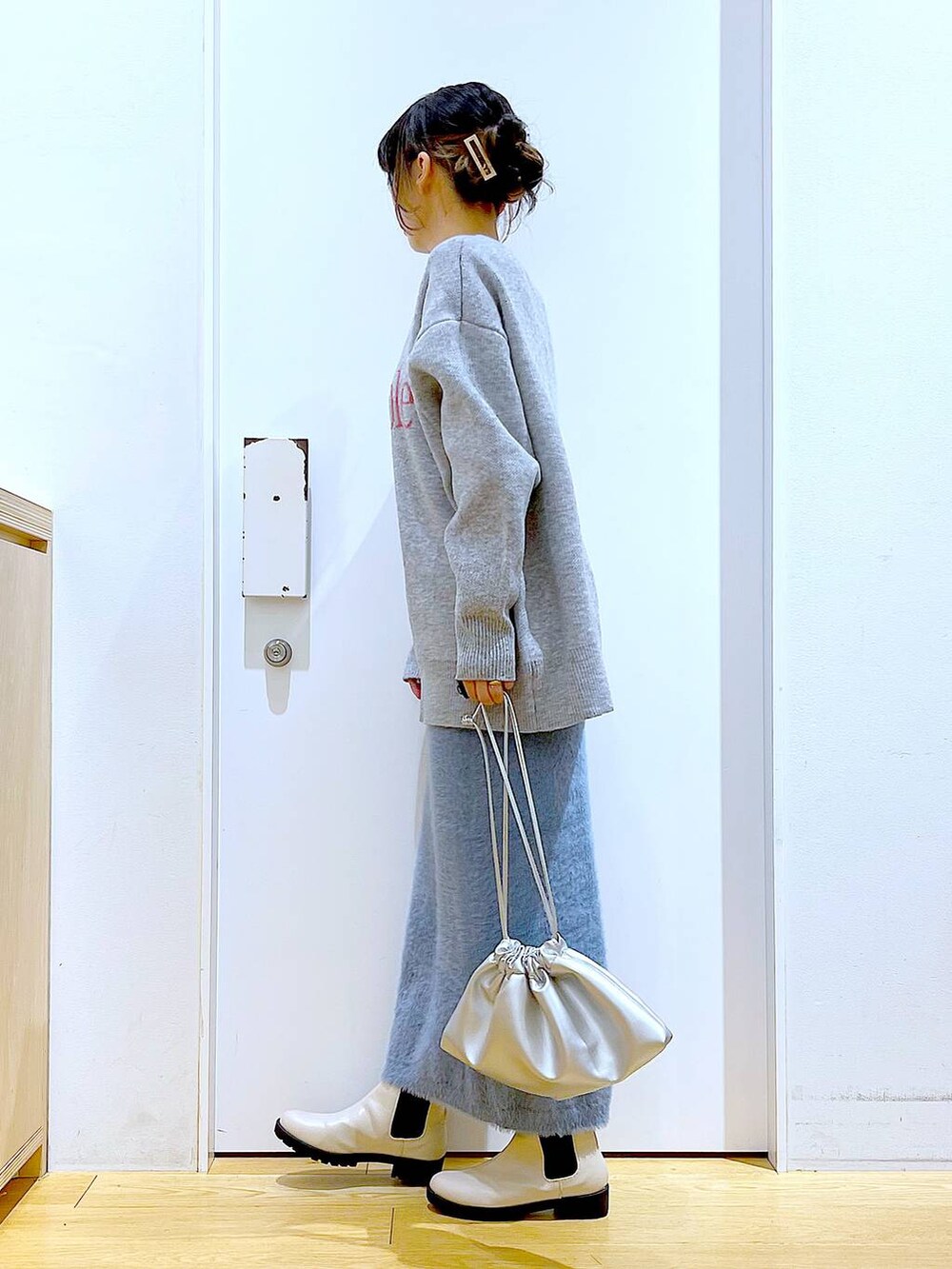 ベージュ系のブーツ、シルバー系のショルダーバッグ、ブルー系のスカートを着用したレディースの冬コーディネートの3枚目の写真