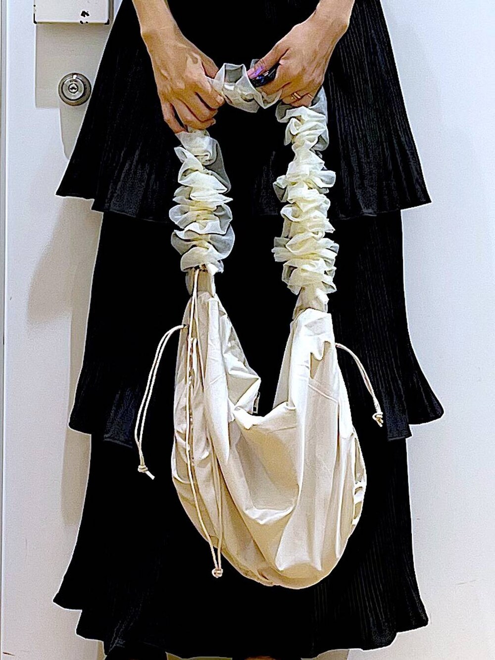 ブラック系のスカート、ブラック系のサンダル、ホワイト系のベストを着用したレディースの秋コーディネートの9枚目の写真