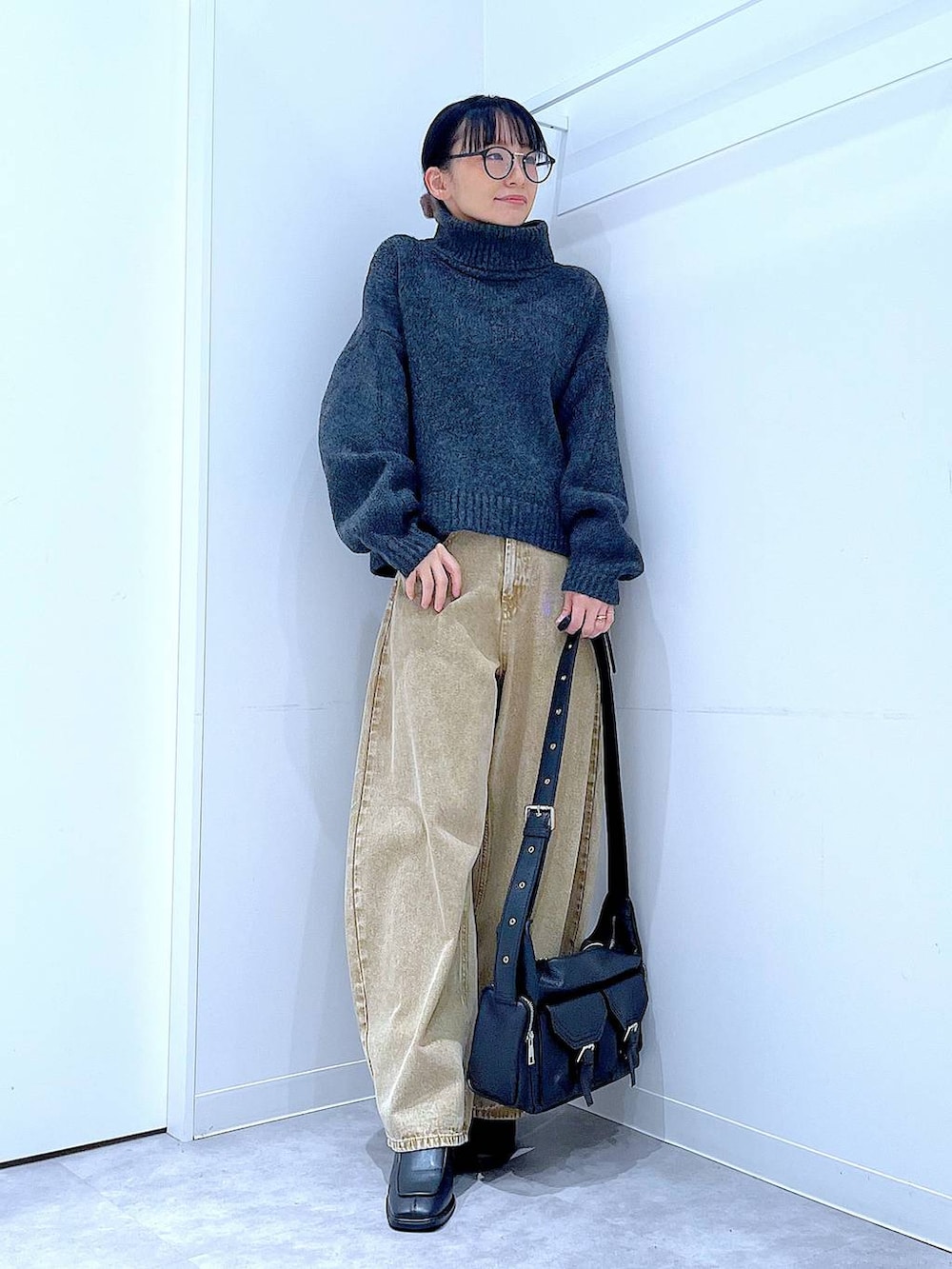 ベージュ系のデニムパンツ、ブラック系のブーツ、グレー系のニット/セーターを着用したレディースの冬コーディネートの2枚目の写真