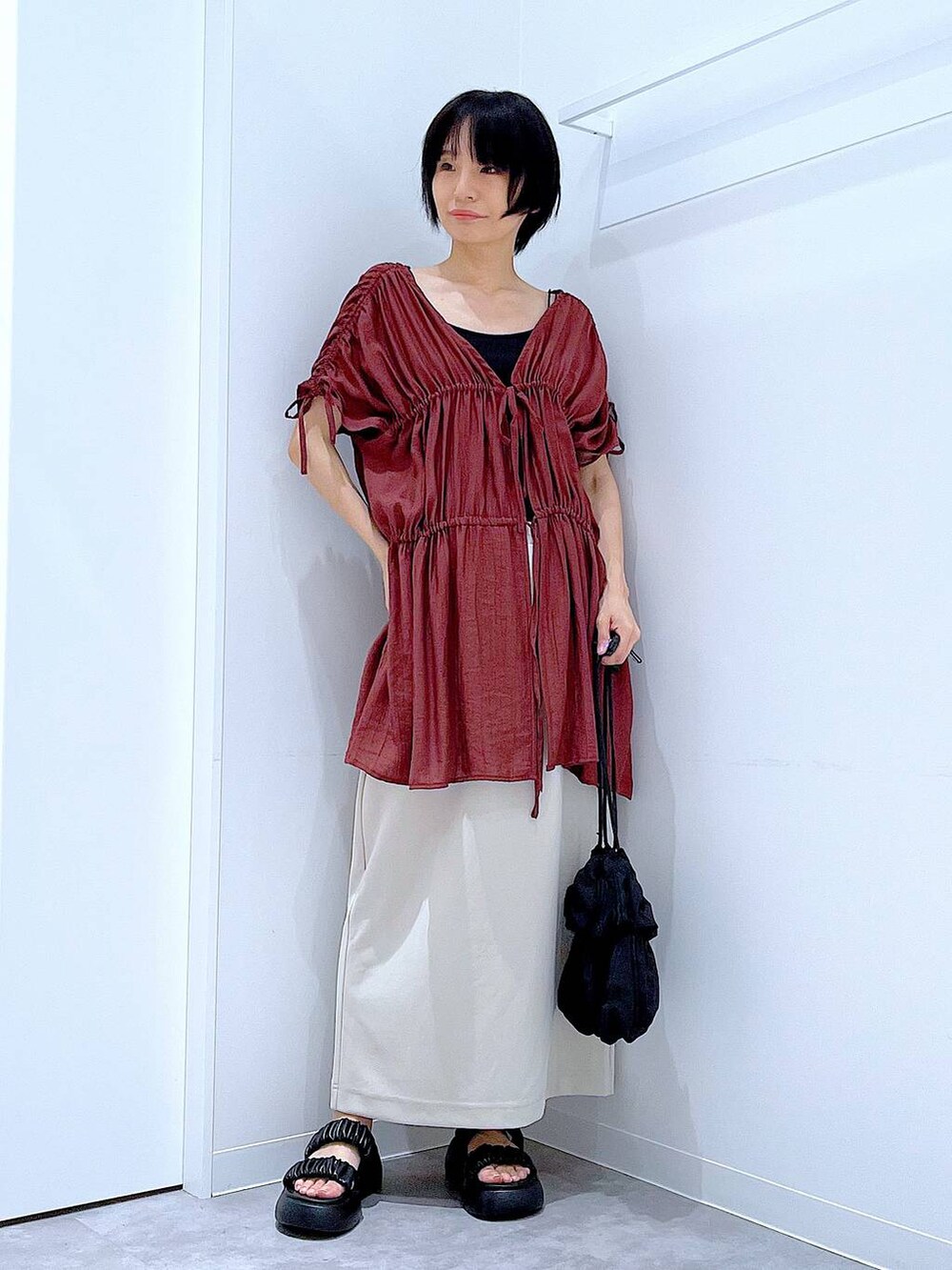 ブラック系のサンダル、ベージュ系のスカート、ブラック系のショルダーバッグを着用したレディースの秋コーディネートの2枚目の写真