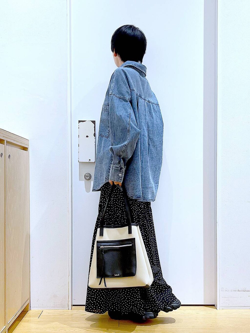 ブラック系のブーツ、ブルー系のシャツ/ブラウス、ホワイト系のトートバッグを着用したレディースの春コーディネートの3枚目の写真