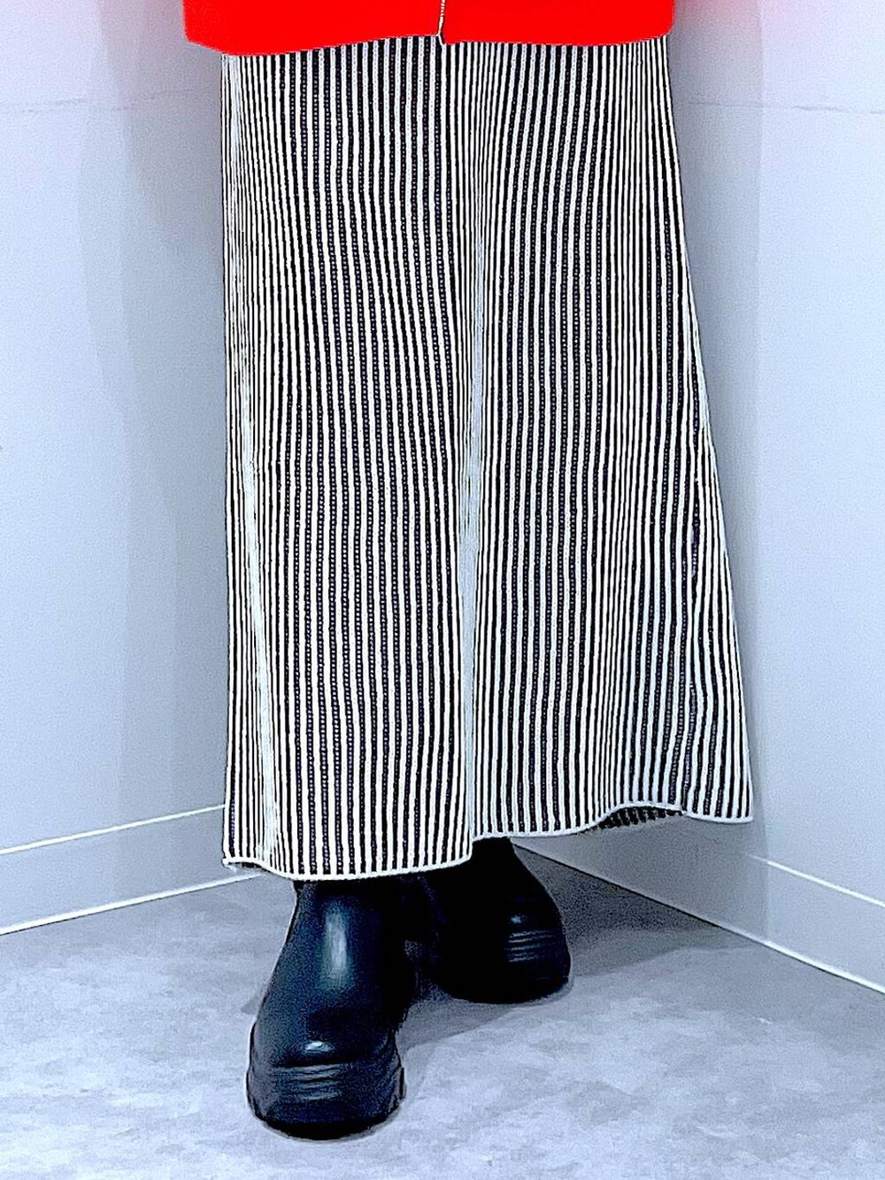 ブラック系のブーツ、ベージュ系のスカート、ホワイト系のハンドバッグを着用したレディースの秋コーディネートの8枚目の写真