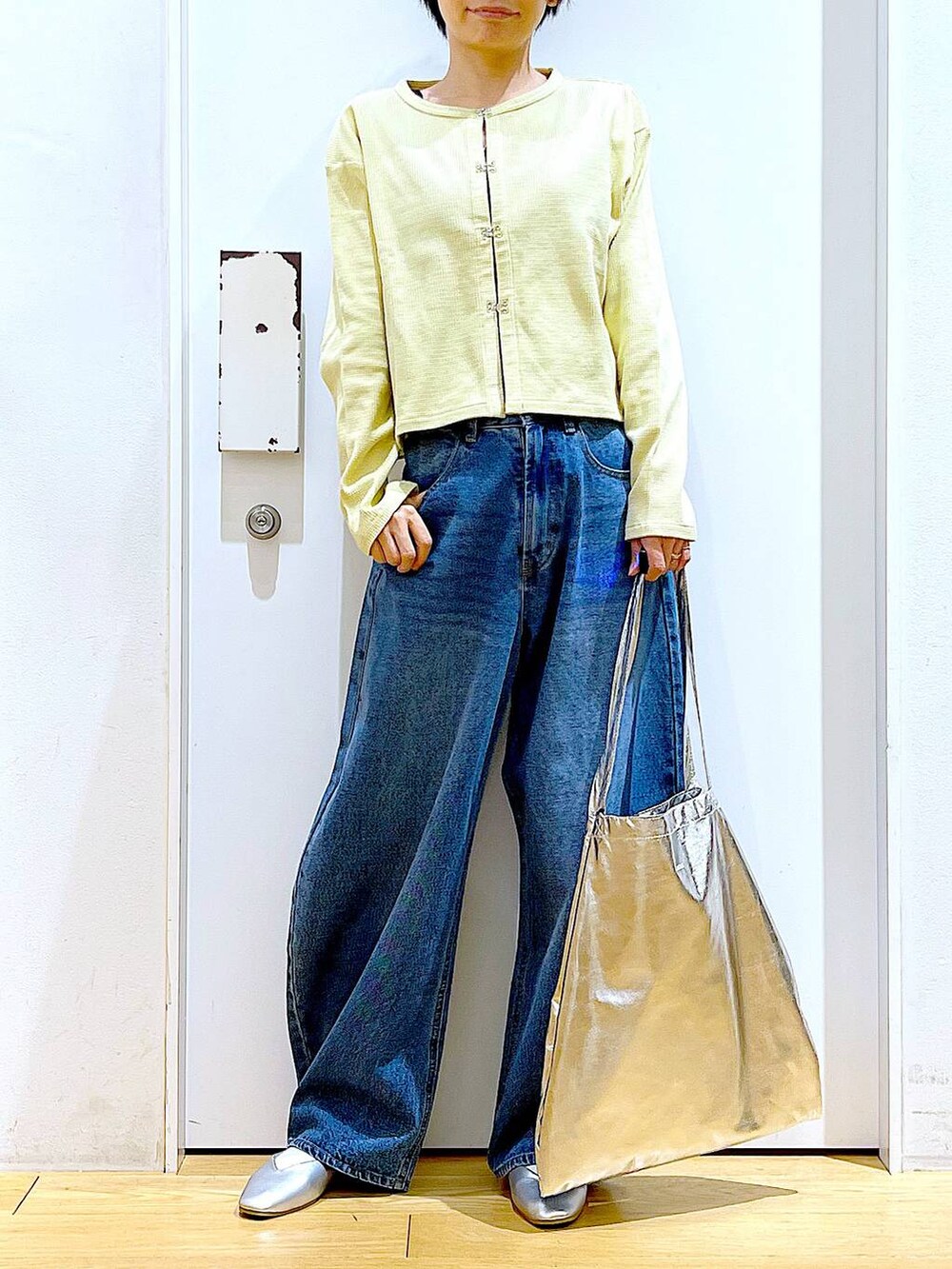 シルバー系のトートバッグ、ブルー系のデニムパンツ、シルバー系のパンプスを着用したレディースの春コーディネートの6枚目の写真