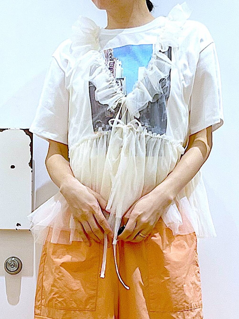 ホワイト系のスニーカー、ホワイト系のショルダーバッグ、オレンジ系のカーゴパンツを着用したレディースの夏コーディネートの6枚目の写真