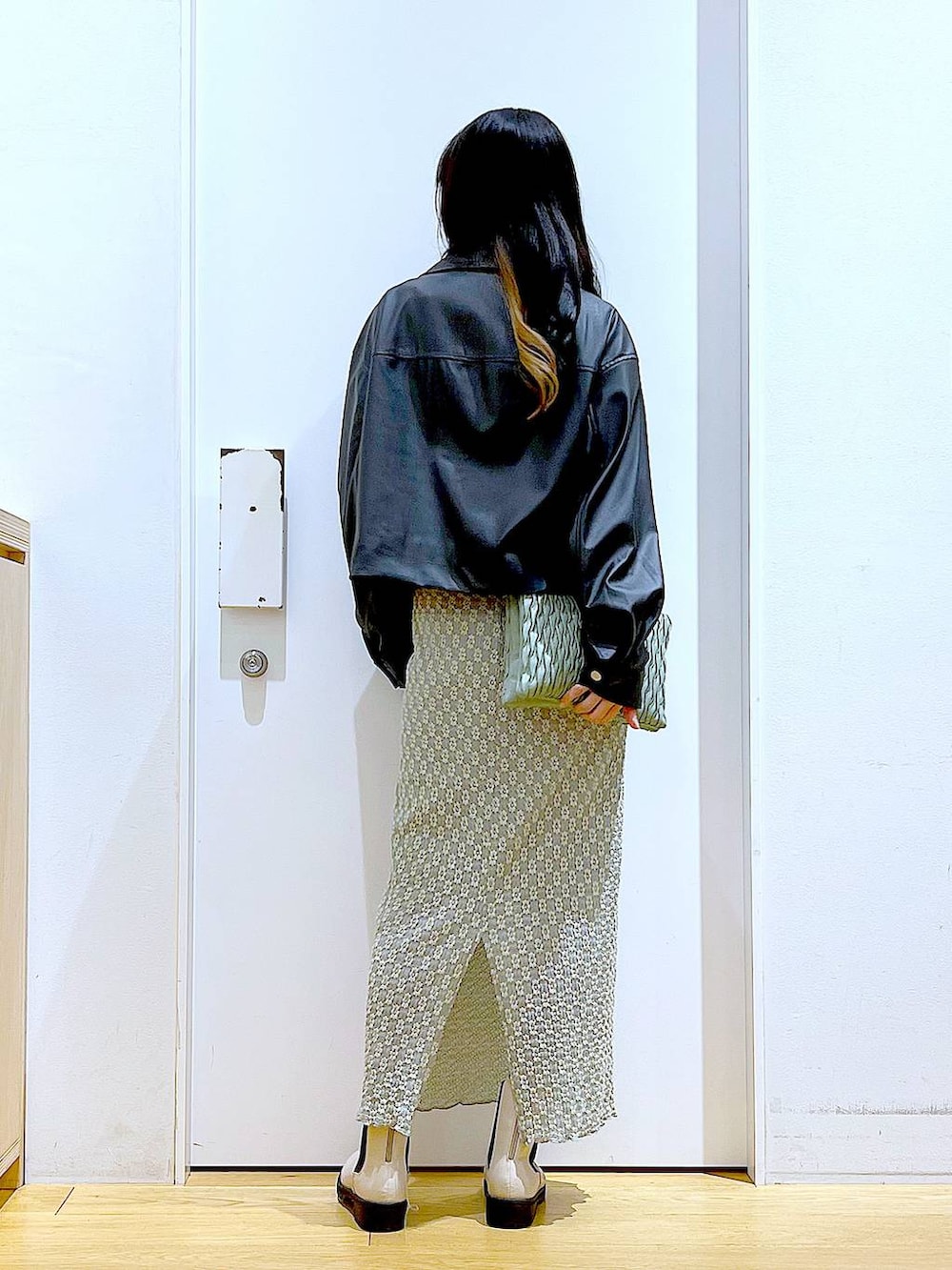 グリーン系のショルダーバッグ、ベージュ系のブーツ、グリーン系のスカートを着用したレディースの春コーディネートの5枚目の写真