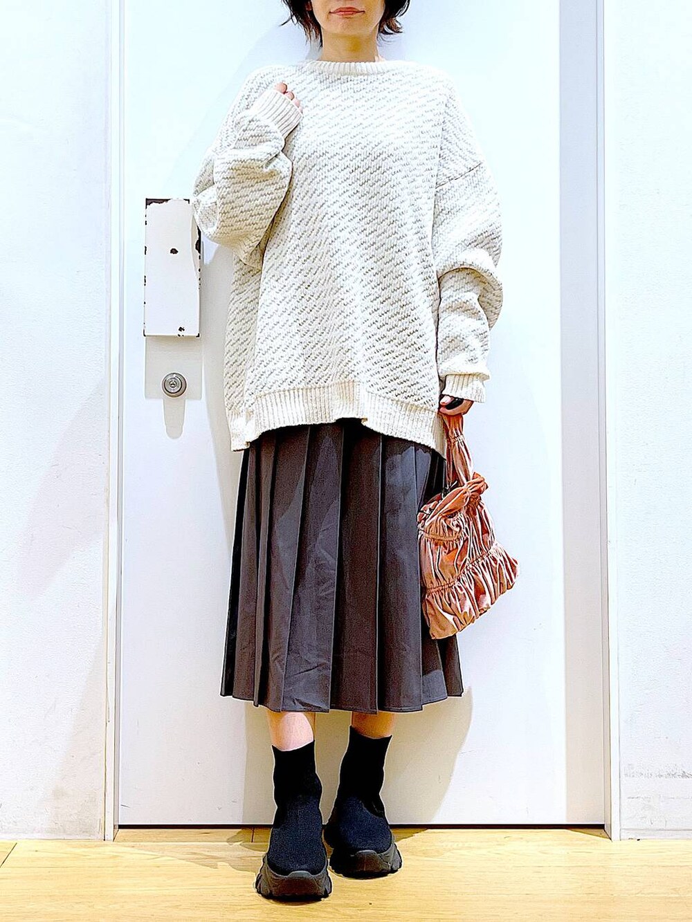 ベージュ系のニット/セーター、ピンク系のショルダーバッグ、ブラック系のブーツを着用したレディースの冬コーディネートの6枚目の写真