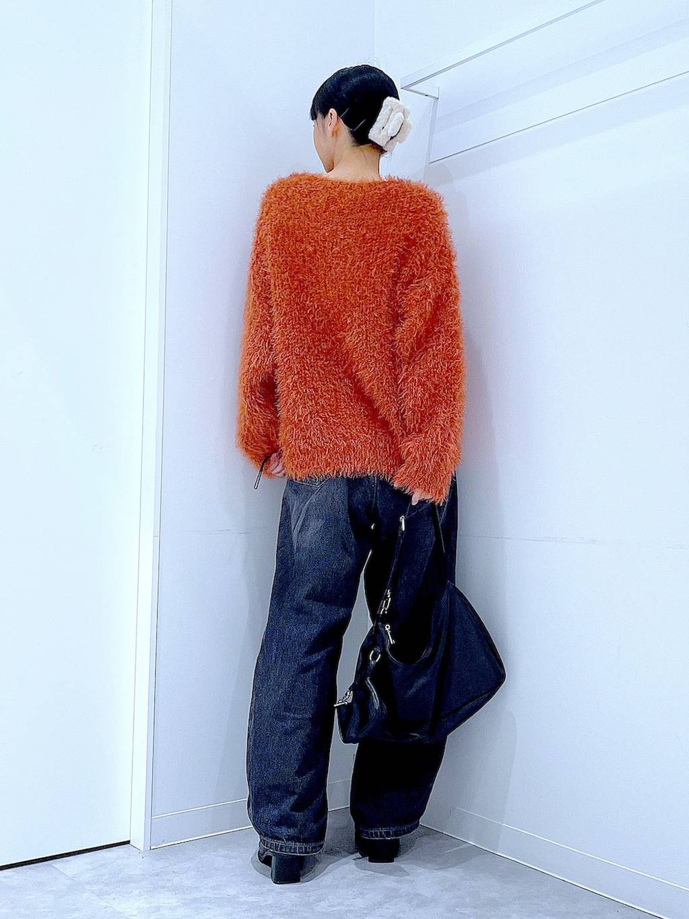 ブラック系のデニムパンツ、ブラック系のブーツ、ブラック系のショルダーバッグを着用したレディースの秋コーディネートの5枚目の写真