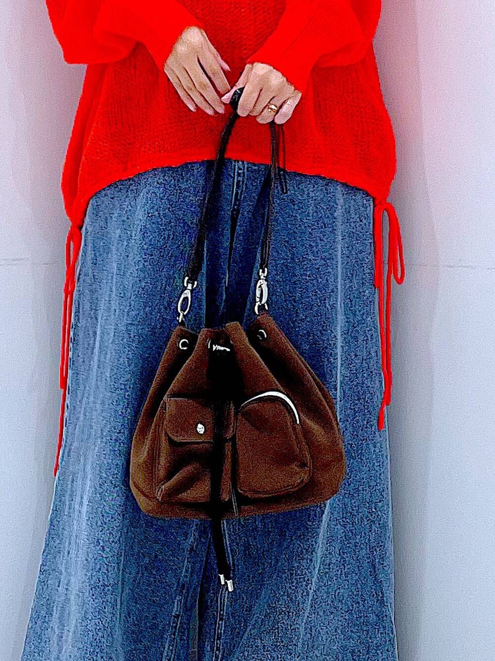 ブラウン系のショルダーバッグ、ブルー系のデニムパンツ、ブラック系のブーツを着用したレディースの秋コーディネートの9枚目の写真