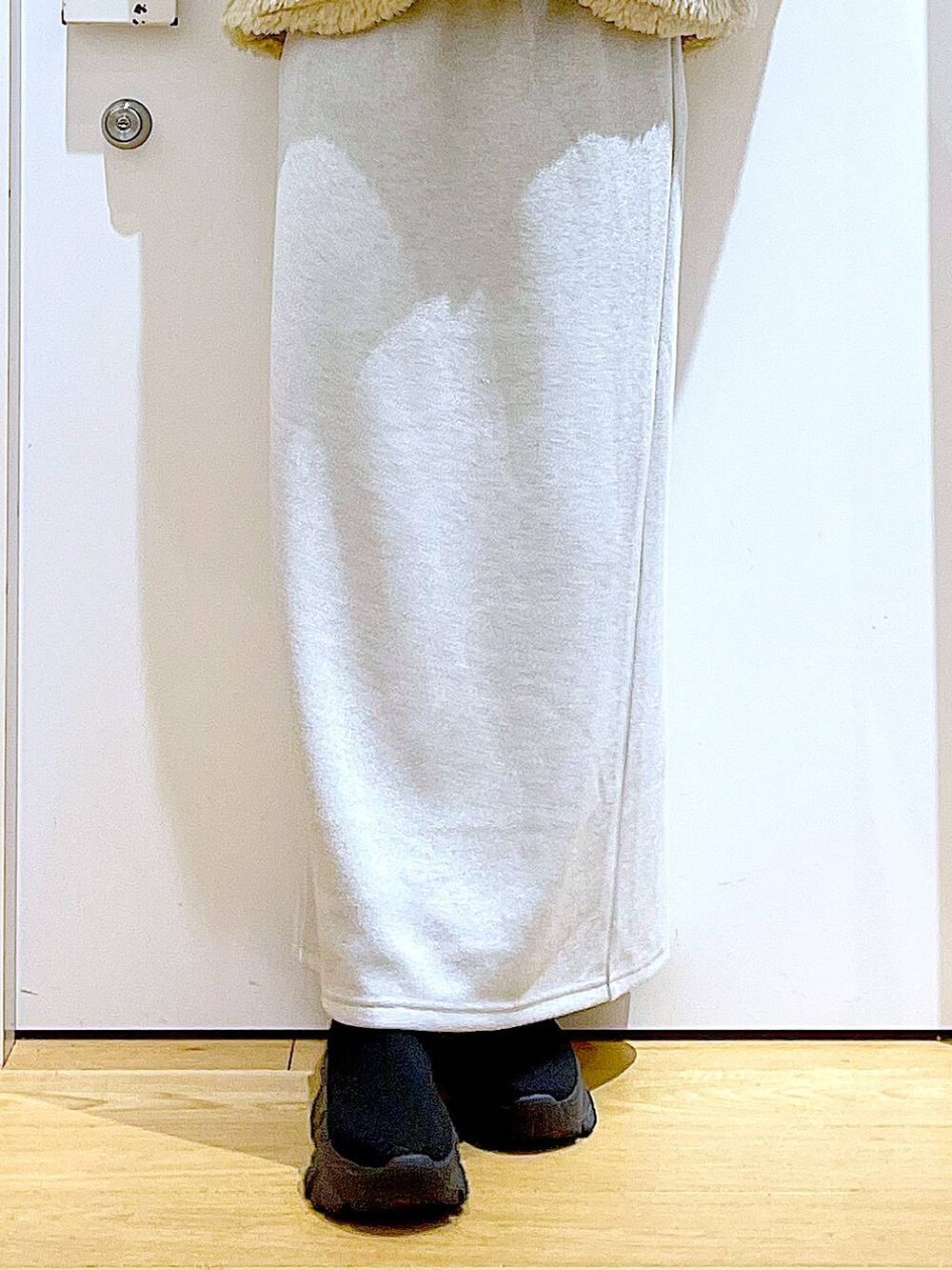 ホワイト系のブルゾン、ブラック系のブーツ、ベージュ系のスカートを着用したレディースの冬コーディネートの8枚目の写真