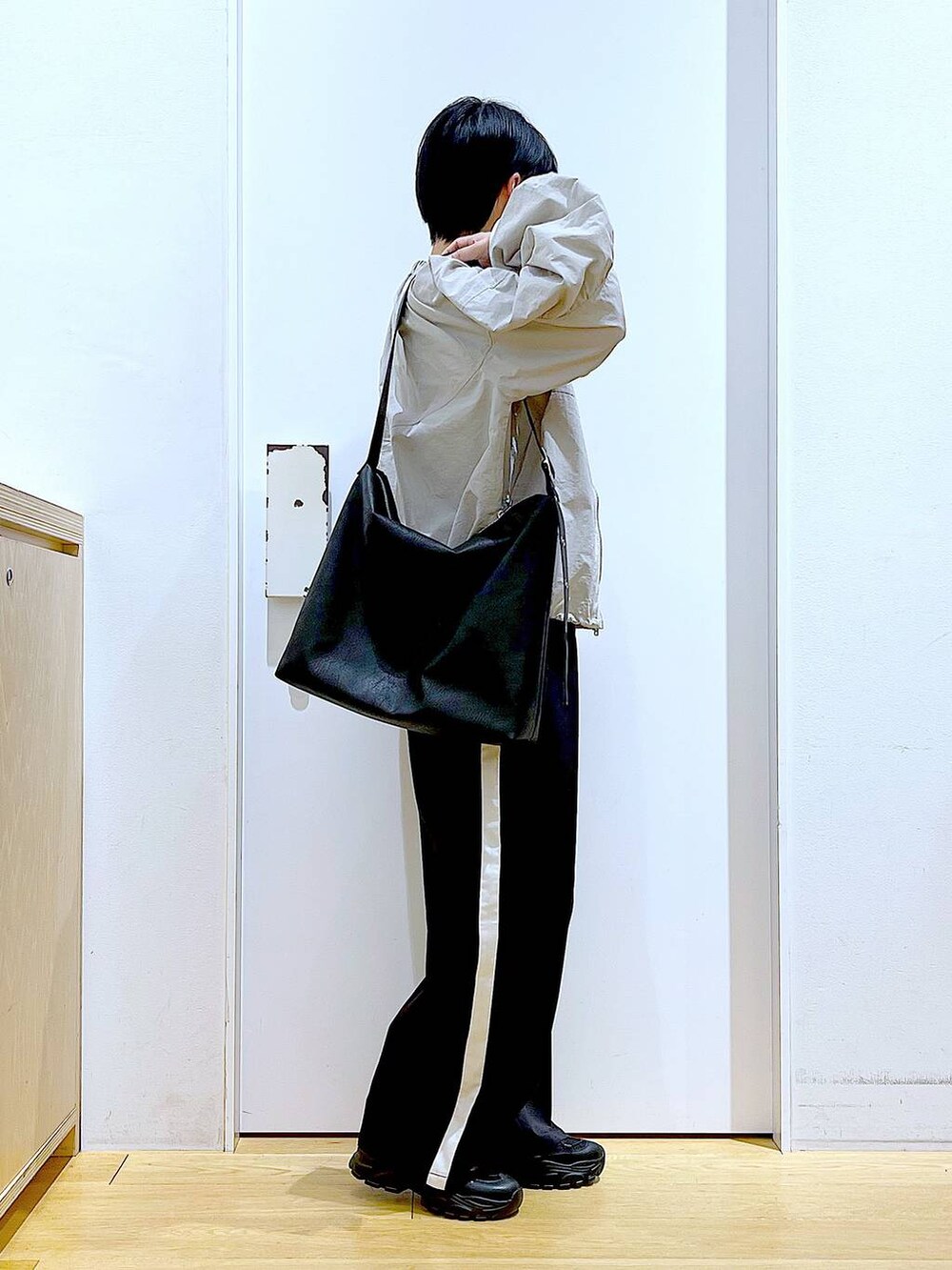 ブラック系のスラックス、ブラック系のスニーカー、ブラック系のショルダーバッグを着用したレディースの春コーディネートの4枚目の写真