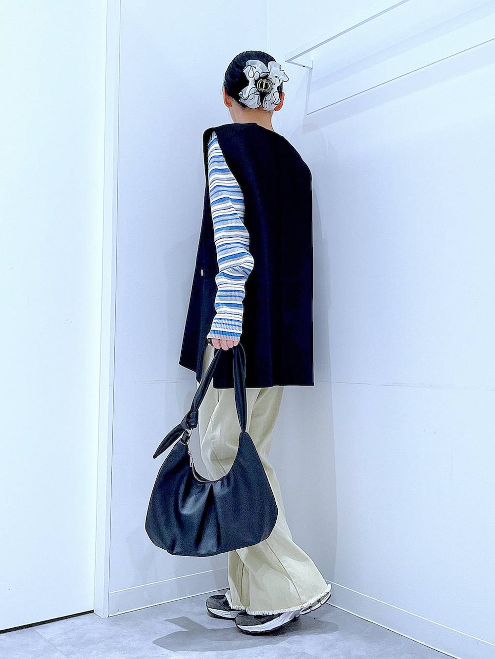 ブルー系のニット/セーター、ブラック系のベスト、ベージュ系のデニムパンツを着用したレディースの冬コーディネートの3枚目の写真