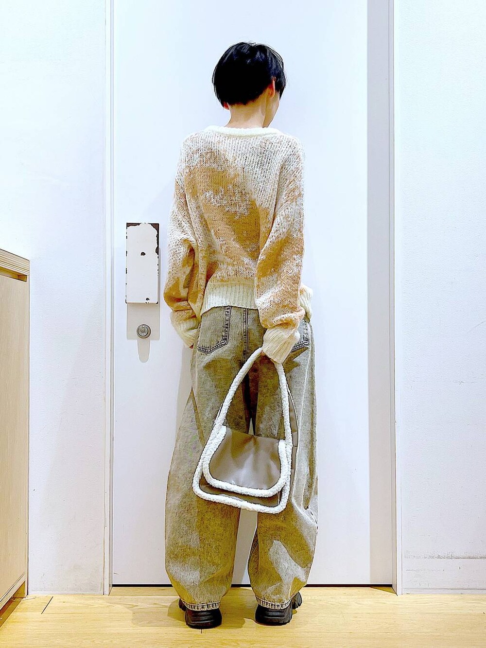 ブラック系のブーツ、ベージュ系のショルダーバッグ、ベージュ系のデニムパンツを着用したレディースの冬コーディネートの5枚目の写真