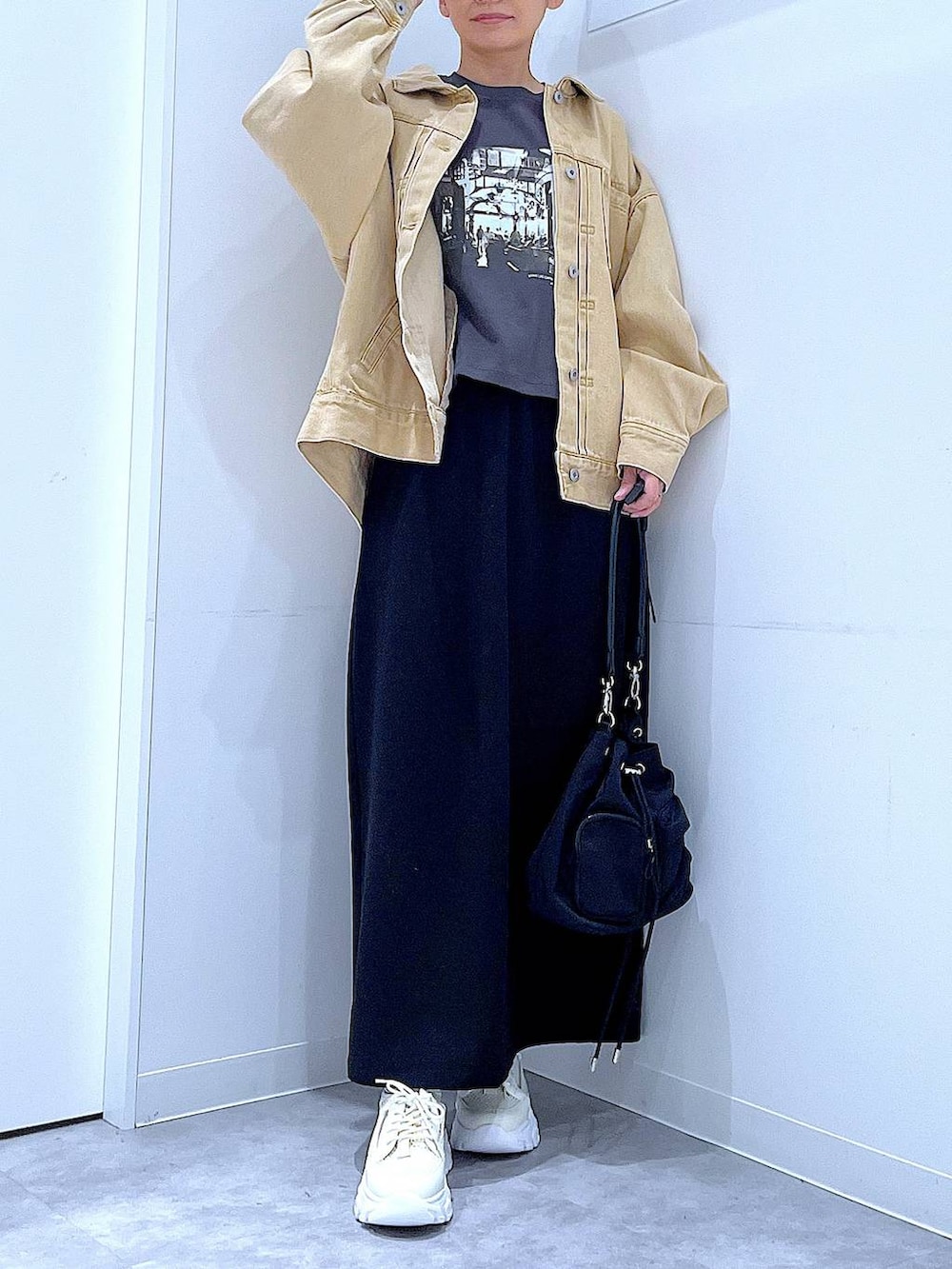 ブラック系のスカート、ベージュ系のデニムジャケット、ブラック系のショルダーバッグを着用したレディースの春コーディネートの6枚目の写真