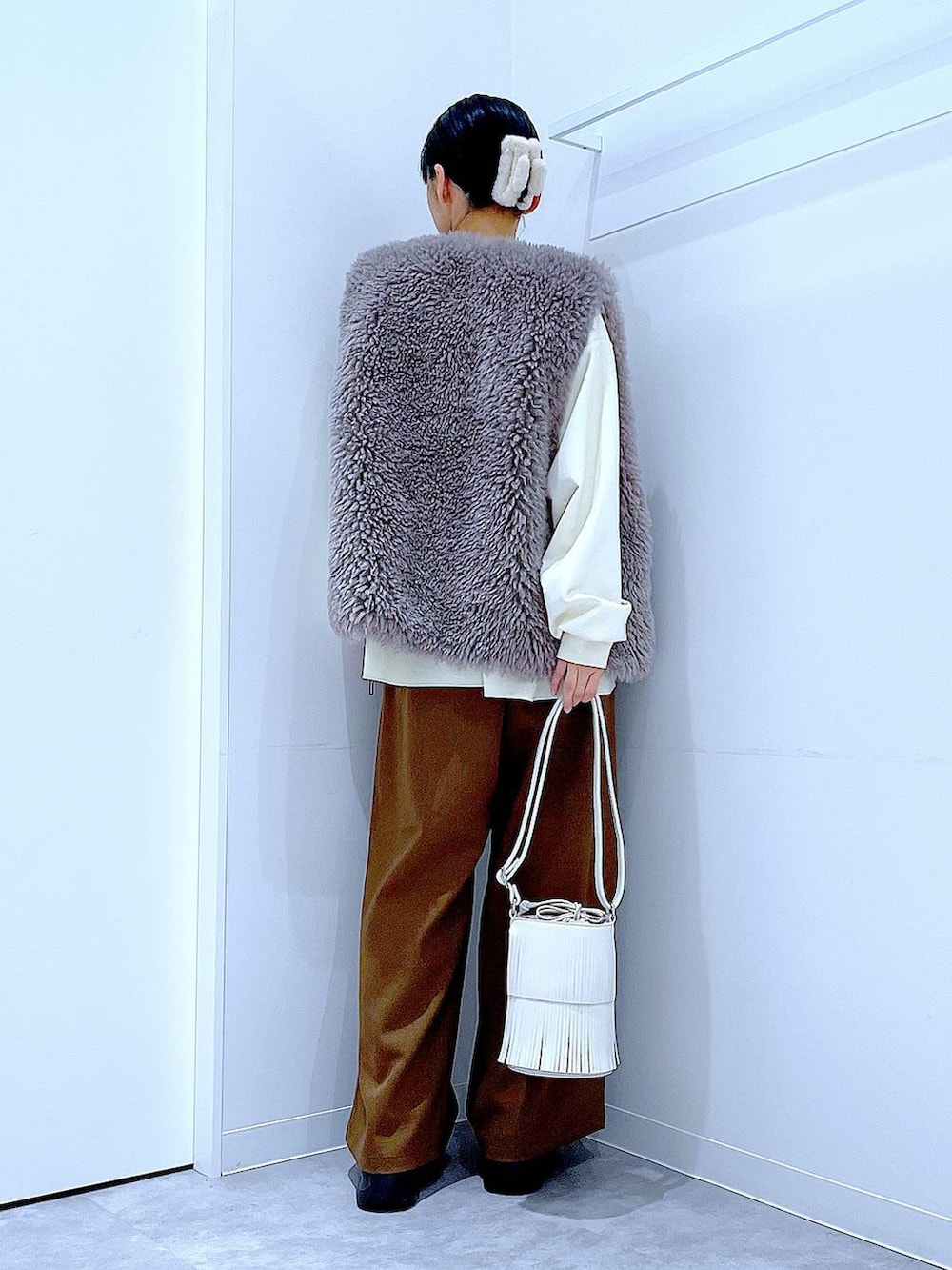 グレー系のベスト、ホワイト系のショルダーバッグ、ブラック系のブーツを着用したレディースの冬コーディネートの5枚目の写真