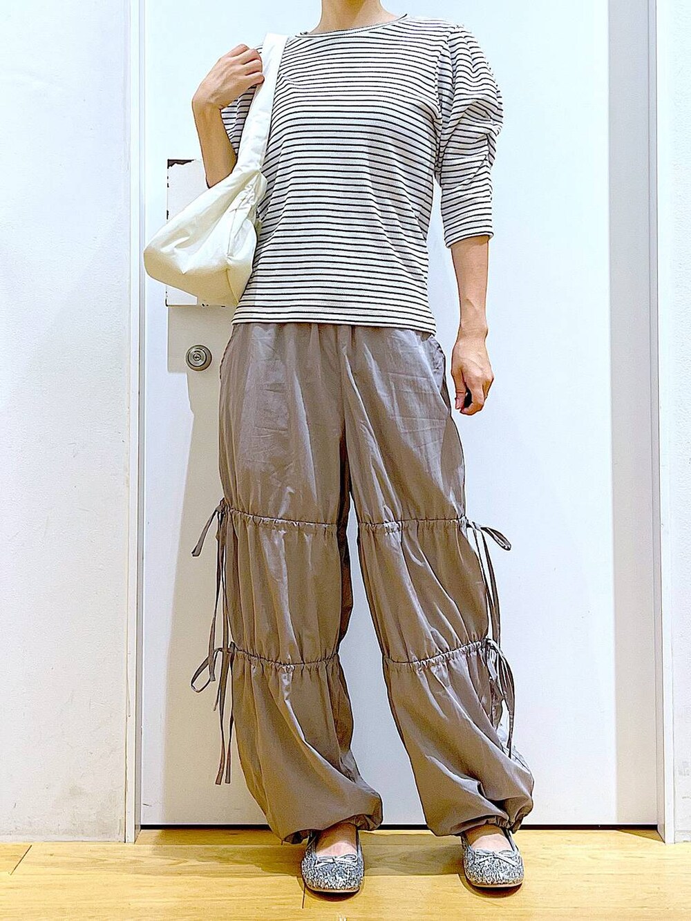 ホワイト系のハンドバッグ、シルバー系のパンプス、グレー系のその他パンツを着用したレディースの秋コーディネートの6枚目の写真