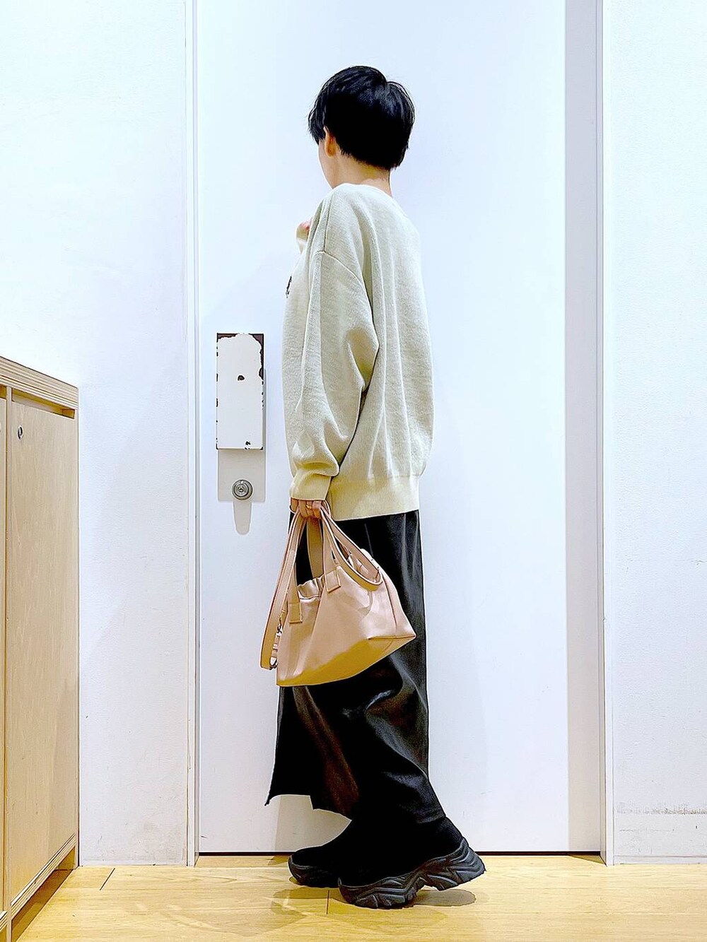 ブラック系のスカート、ブラック系のブーツ、ピンク系のショルダーバッグを着用したレディースの冬コーディネートの3枚目の写真