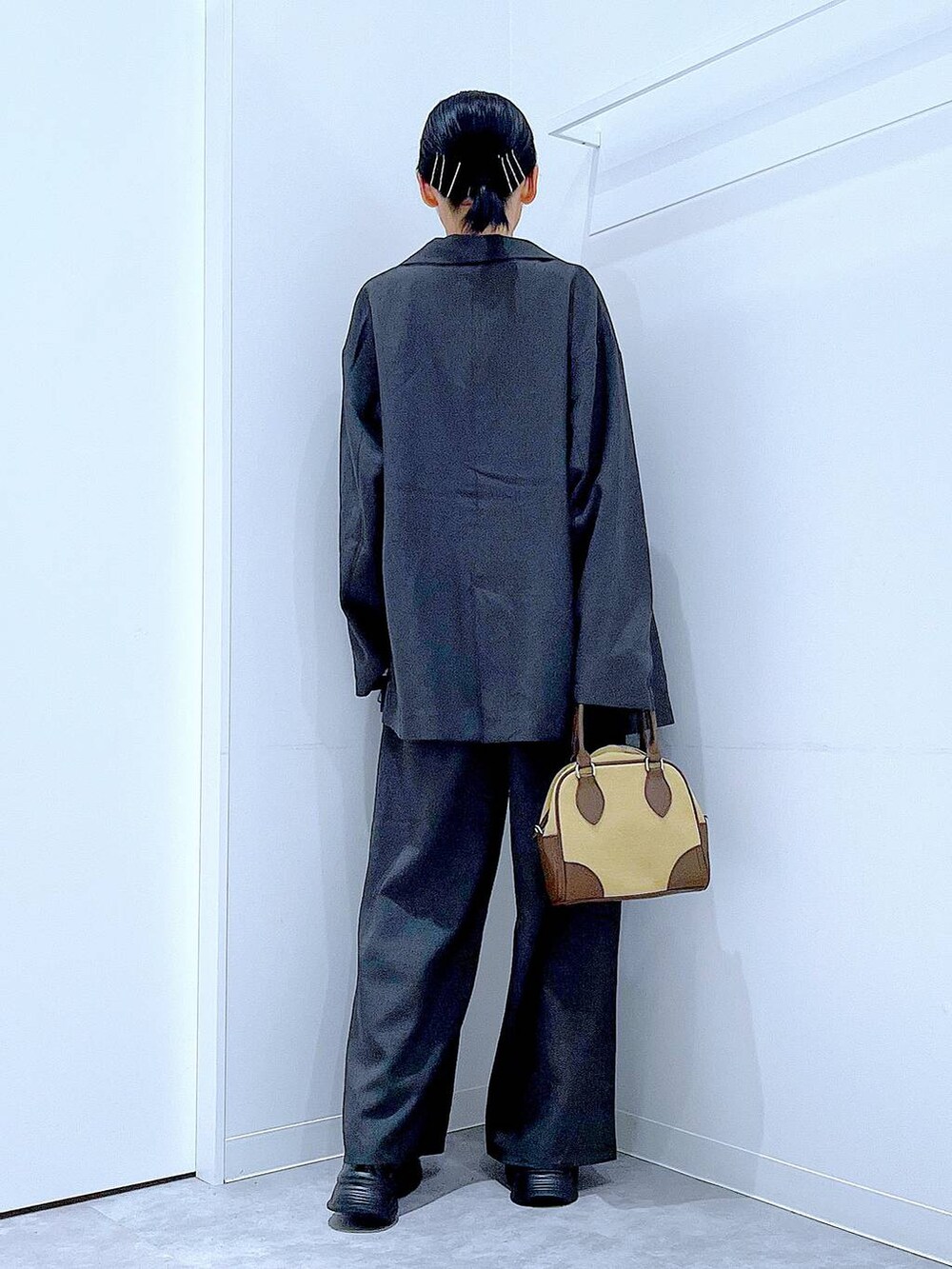 ブラック系のローファー、ベージュ系のハンドバッグ、グレー系のテーラードジャケットを着用したレディースの秋コーディネートの5枚目の写真