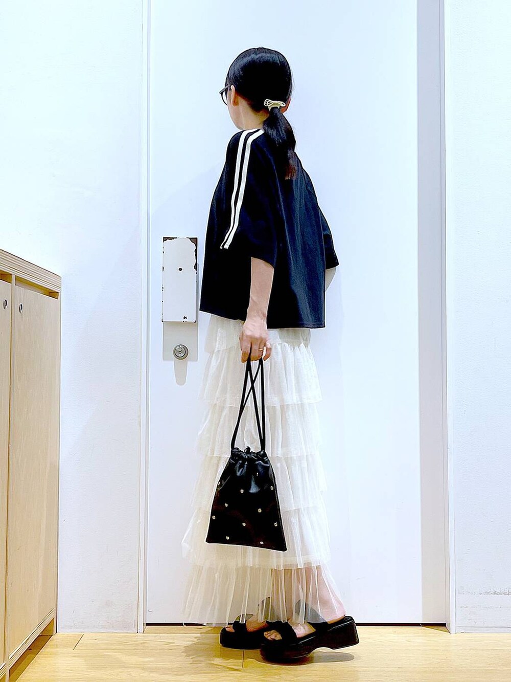 ブラック系のサンダル、ブラック系のショルダーバッグ、ベージュ系のスカートを着用したレディースの夏コーディネートの3枚目の写真