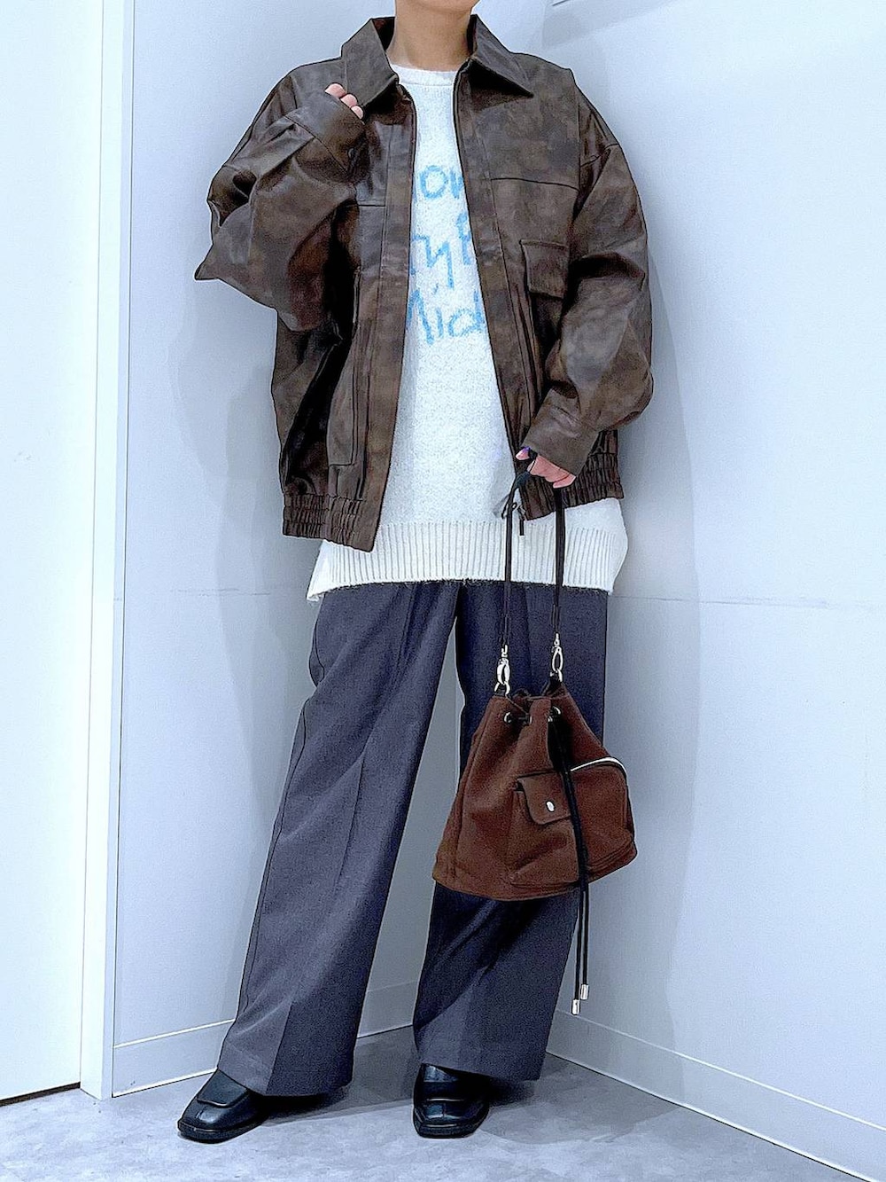 ブラウン系のブルゾン、ブラウン系のショルダーバッグ、ブラック系のブーツを着用したレディースの冬コーディネートの6枚目の写真