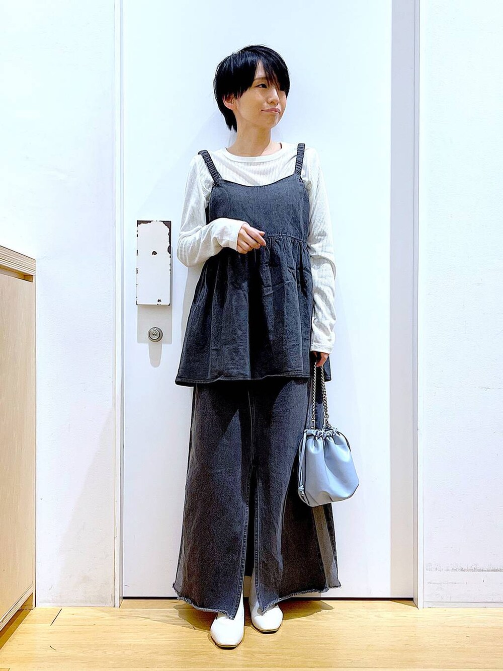 ブルー系のショルダーバッグ、ホワイト系のパンプス、ブラック系のデニムスカートを着用したレディースの春コーディネートの2枚目の写真