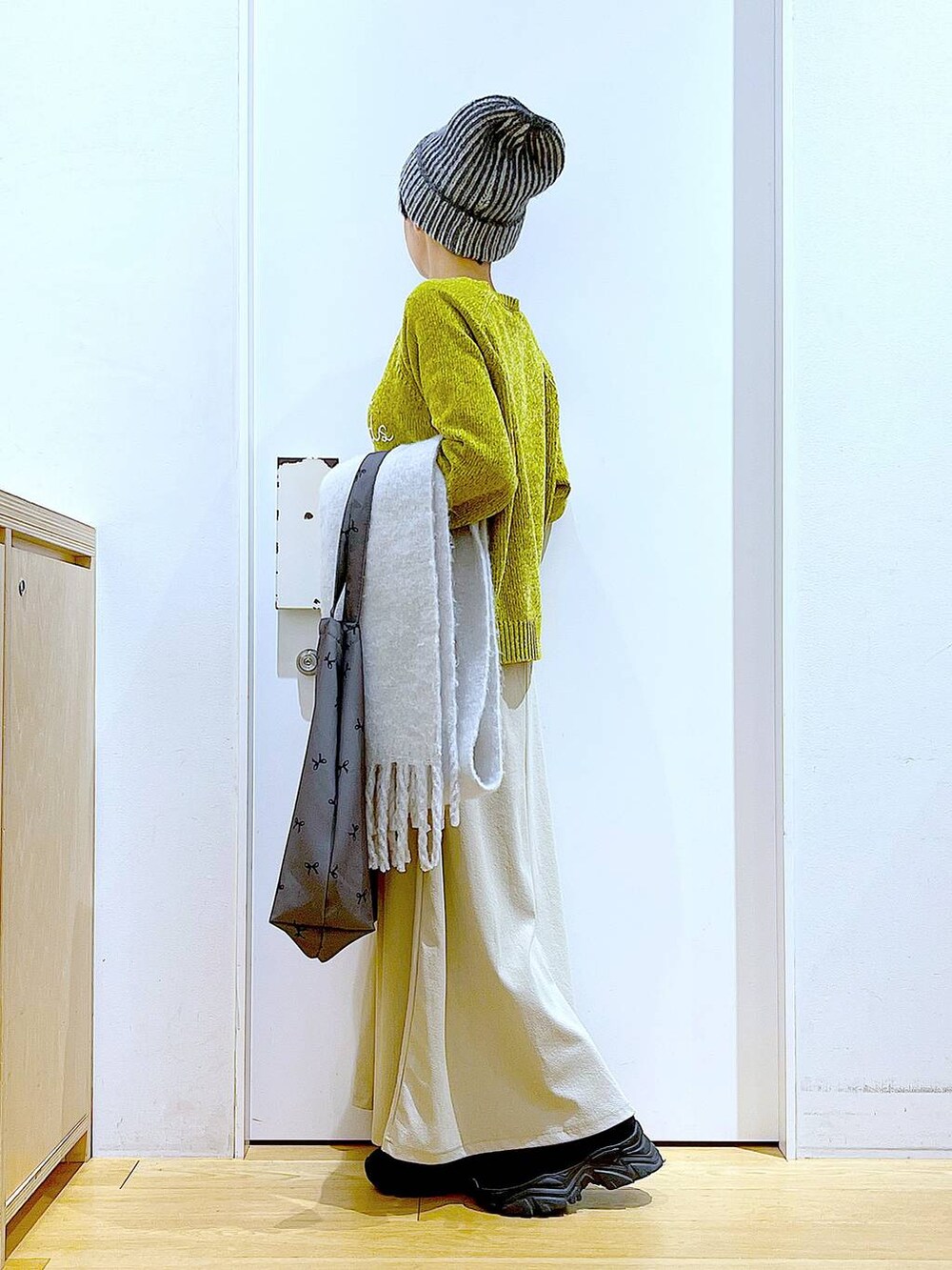 ブラック系のブーツ、その他のトートバッグ、グレー系のスカートを着用したレディースの冬コーディネートの3枚目の写真