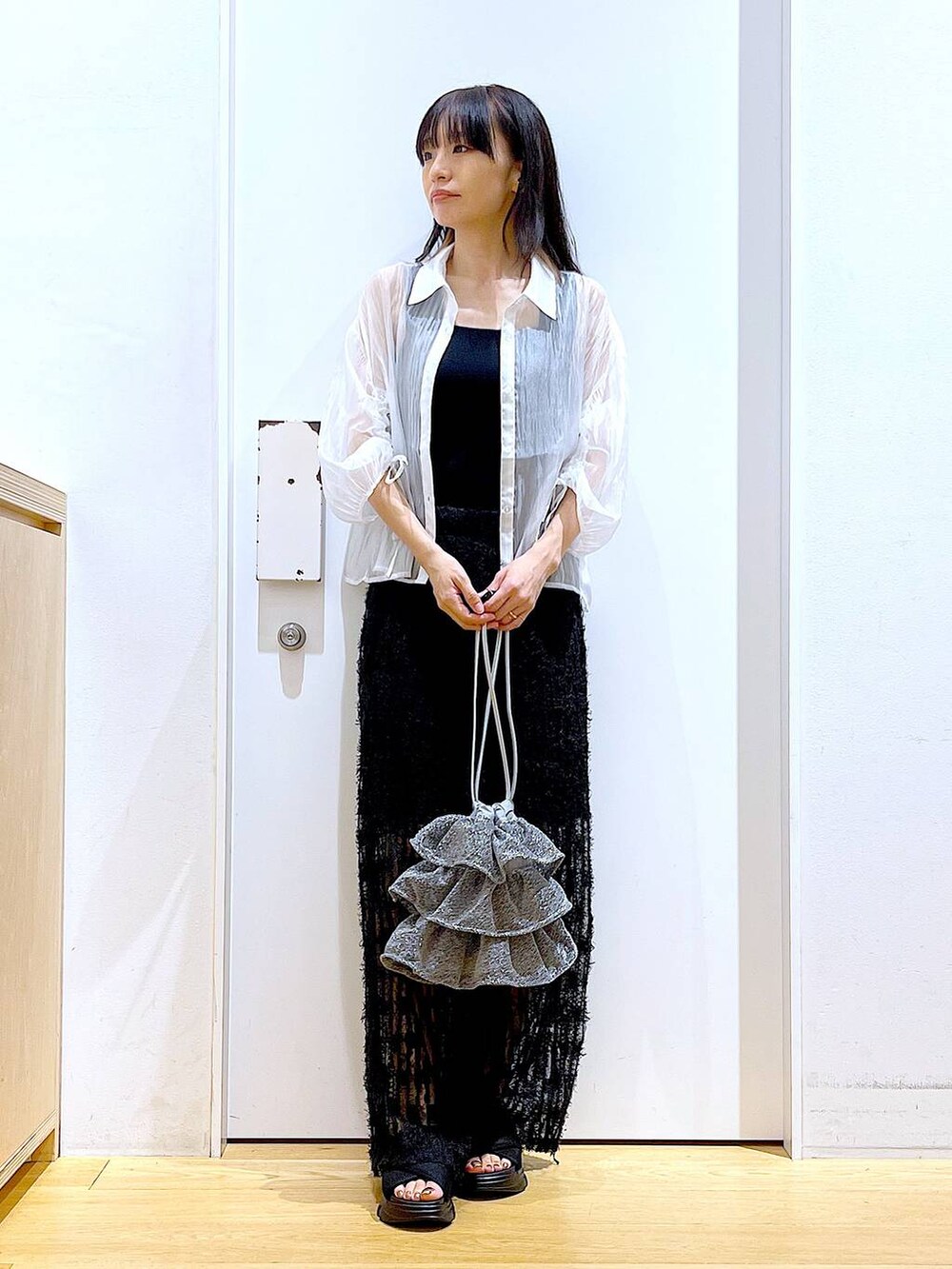 シルバー系のショルダーバッグ、ブラック系のニット/セーター、ブラック系のサンダルを着用したレディースの夏コーディネートの2枚目の写真