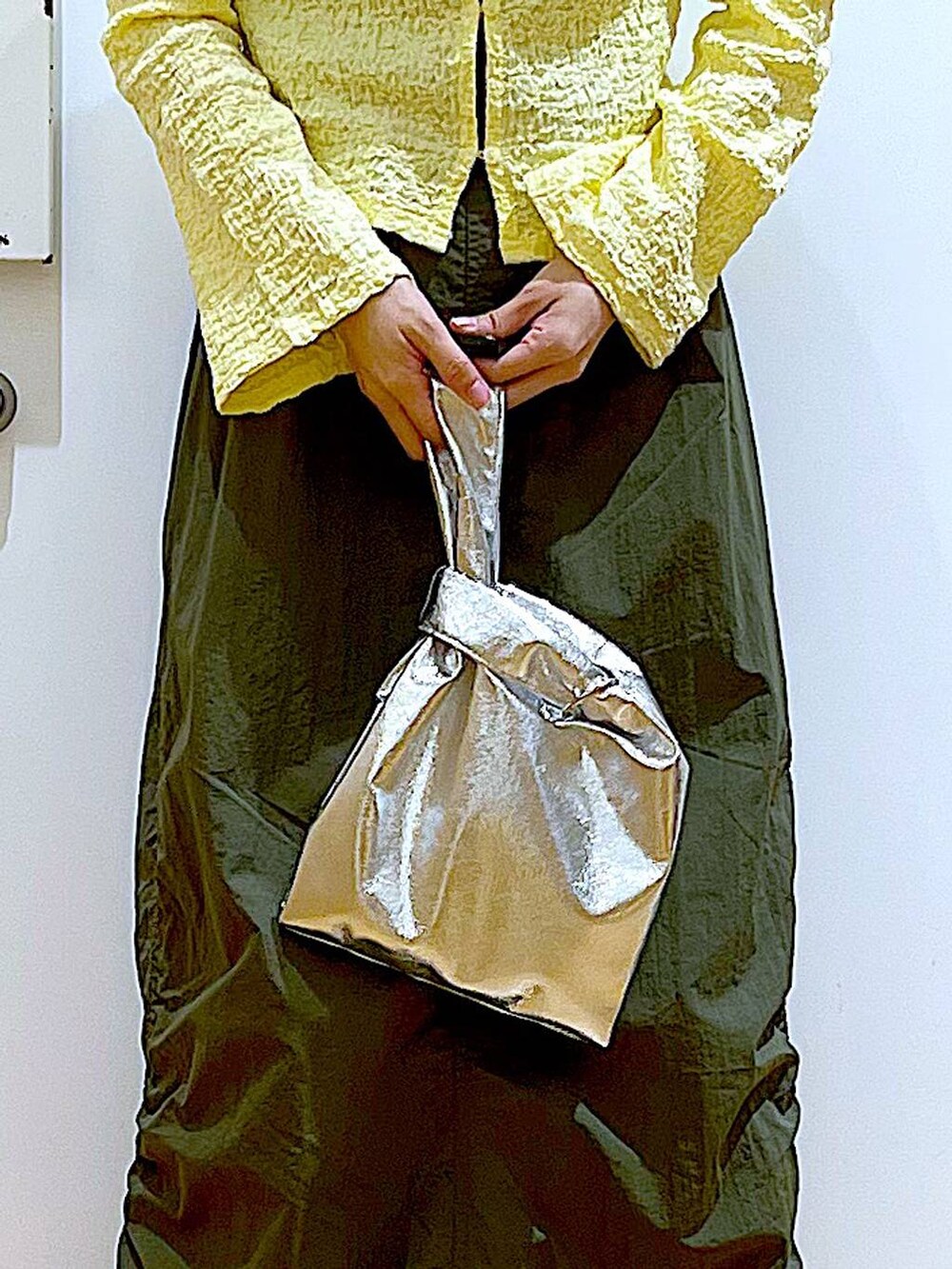 シルバー系のショルダーバッグ、グリーン系のスカート、ブラック系のパンプスを着用したレディースの春コーディネートの9枚目の写真