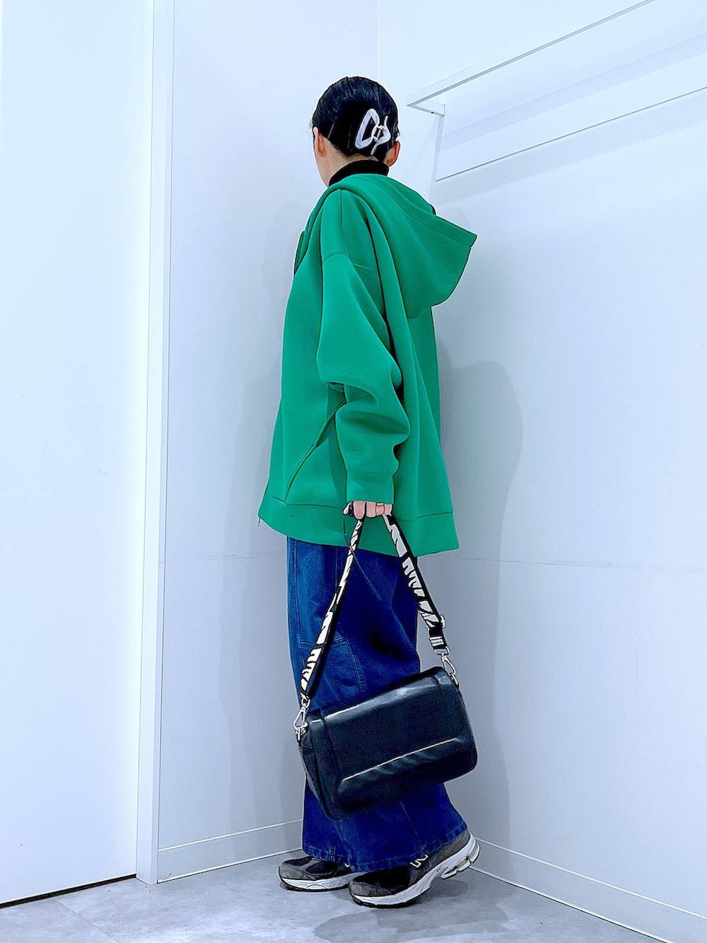 ブラック系のショルダーバッグ、ブラック系のニット/セーター、ブルー系のデニムパンツを着用したレディースの冬コーディネートの3枚目の写真