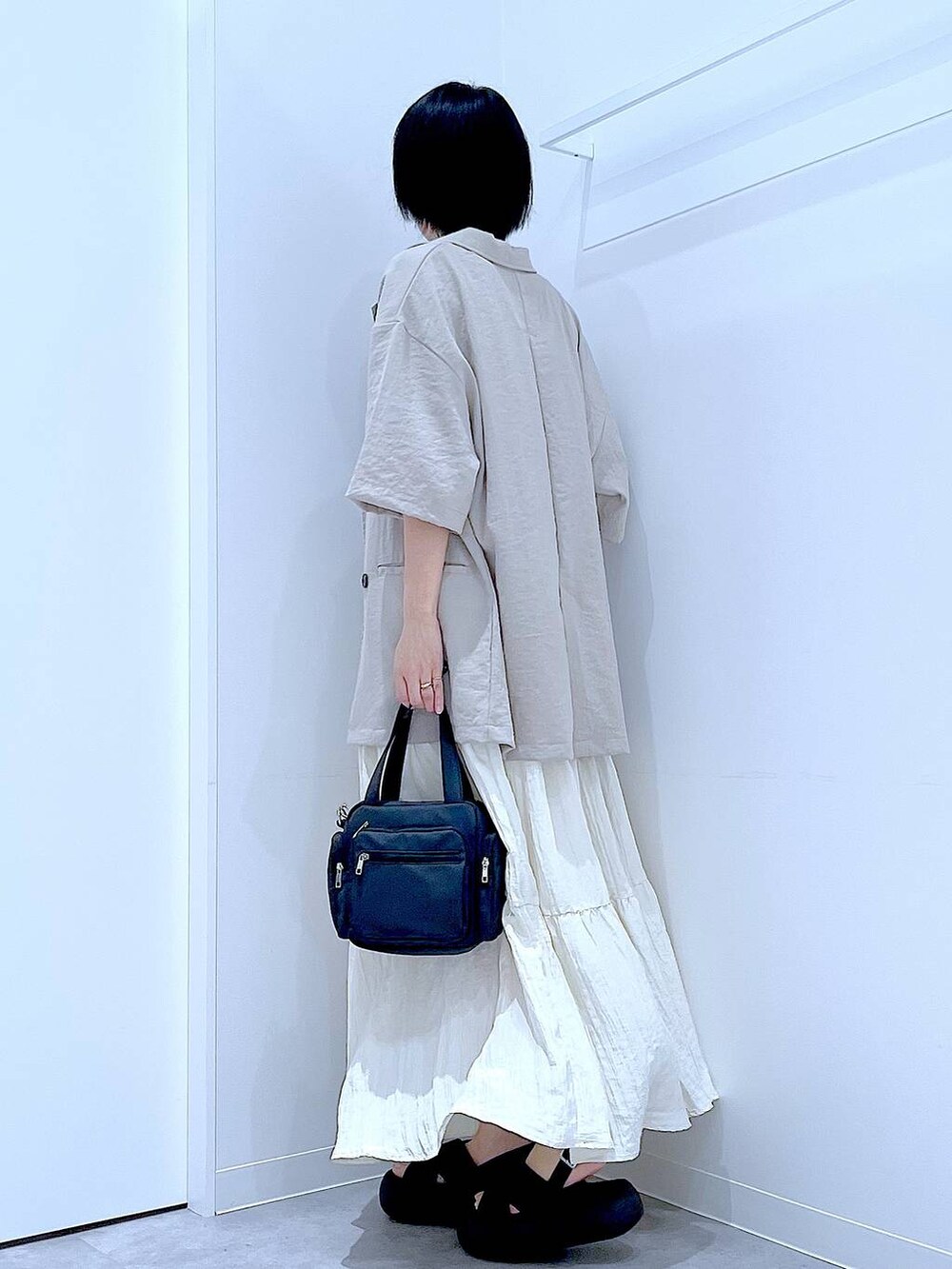 ブラック系のサンダル、ベージュ系のテーラードジャケット、ブラック系のショルダーバッグを着用したレディースの夏コーディネートの3枚目の写真