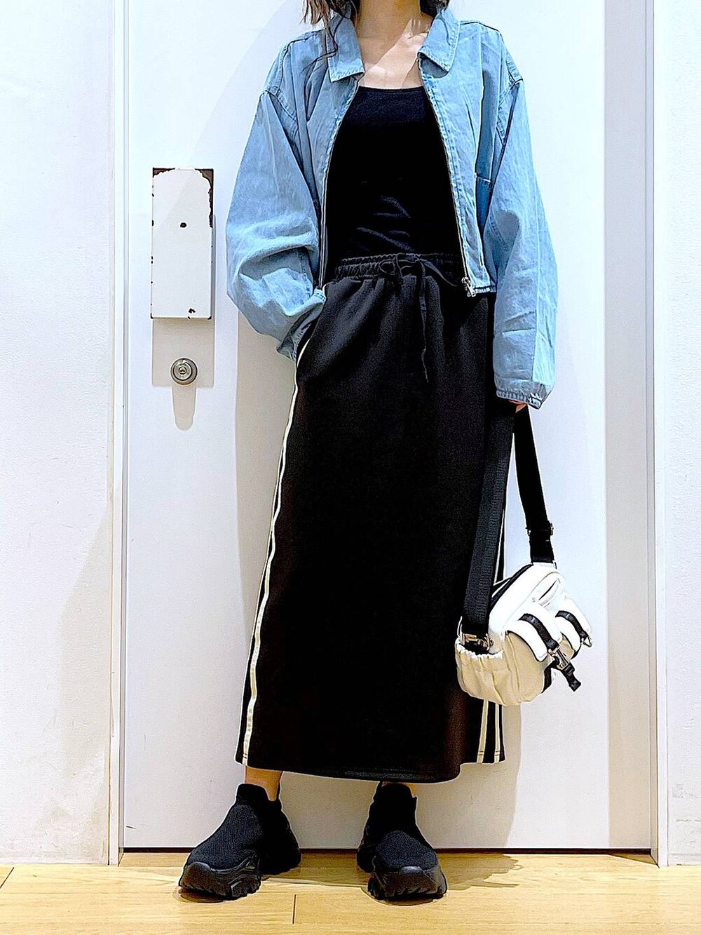 ブルー系のデニムジャケット、ブラック系のスカート、ブラック系のスニーカーを着用したレディースの春コーディネートの6枚目の写真